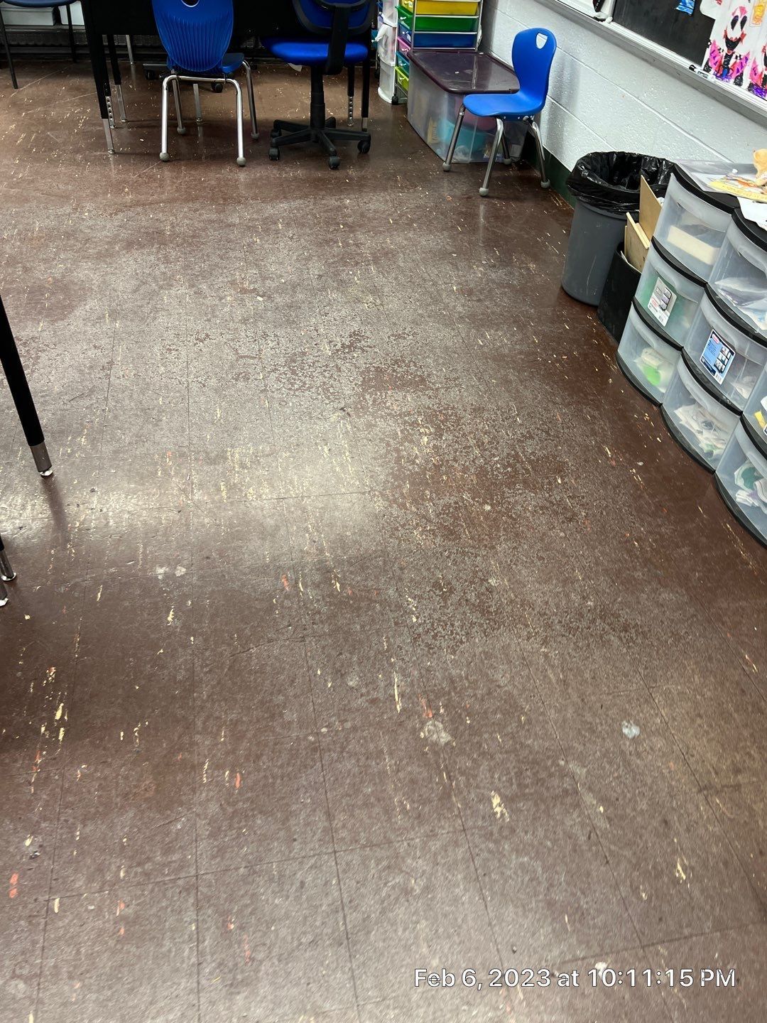 A classroom with a dirty floor and chairs.