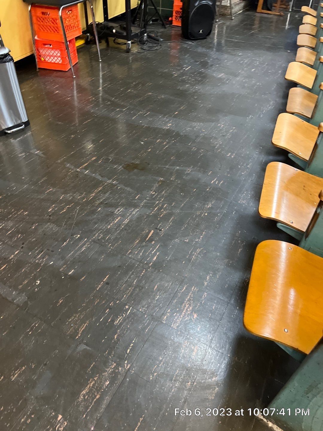 A row of chairs are lined up in a classroom with a dirty floor.