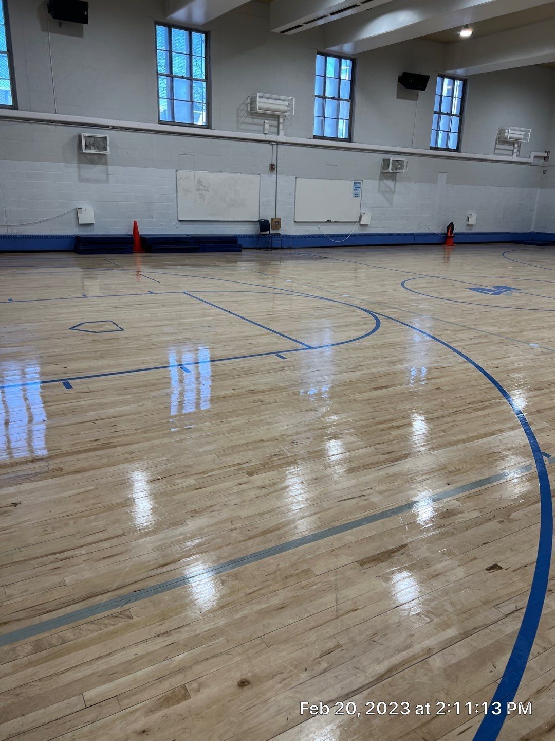 A basketball court with a wooden floor and blue lines.