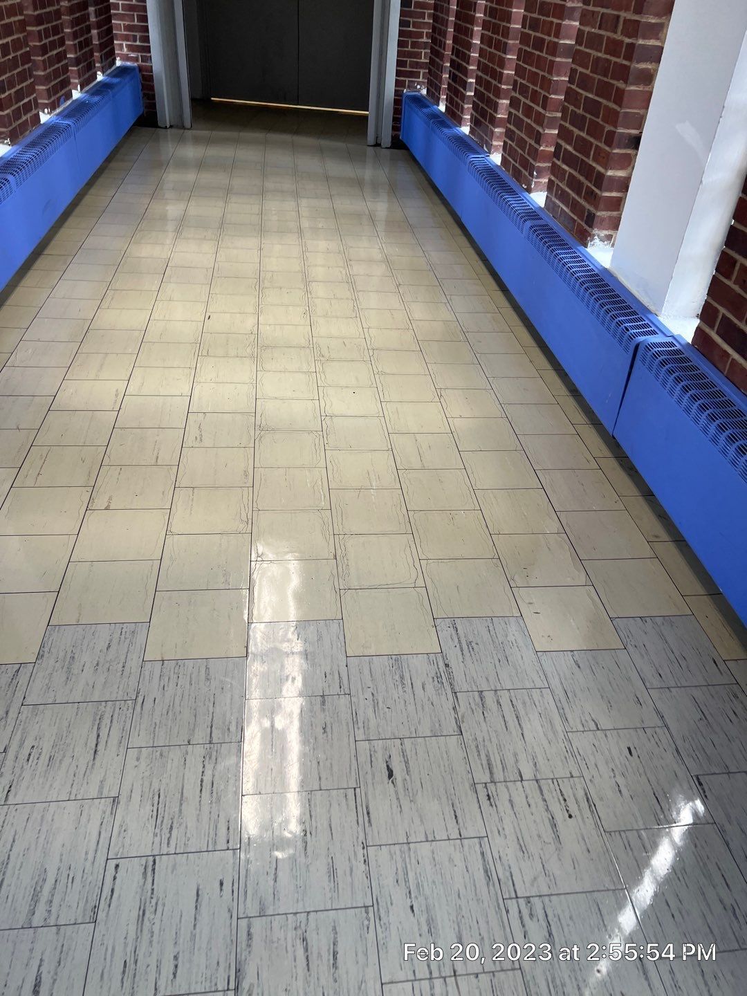 A hallway with a tiled floor and brick walls