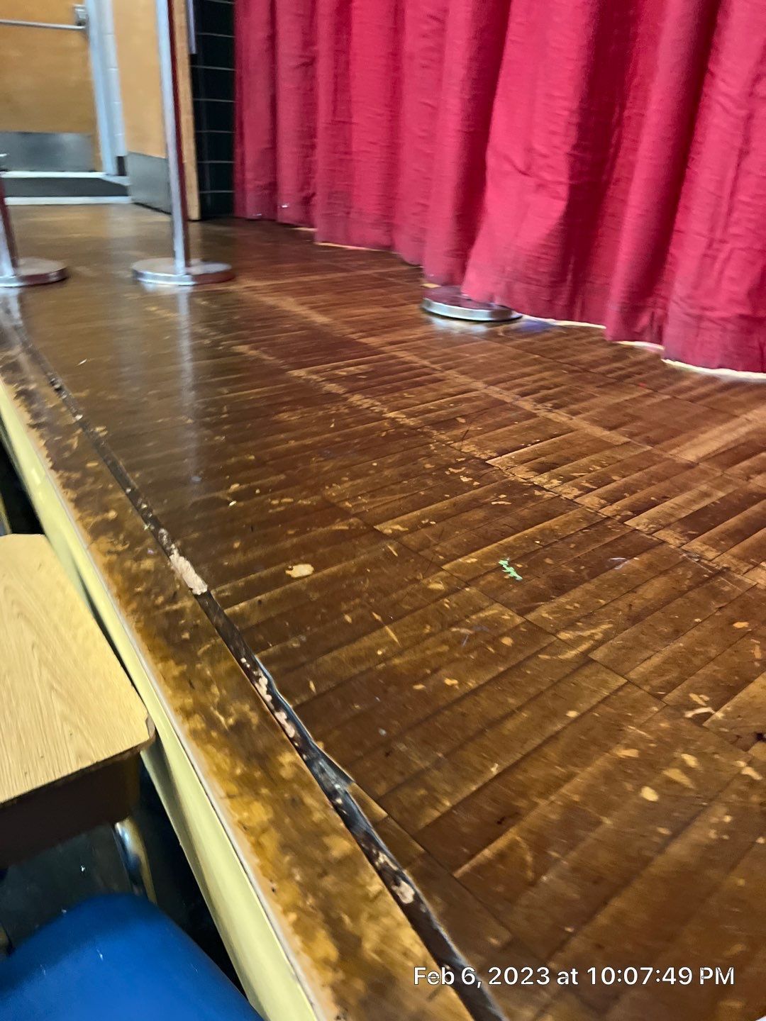 A stage with a wooden floor and red curtains.