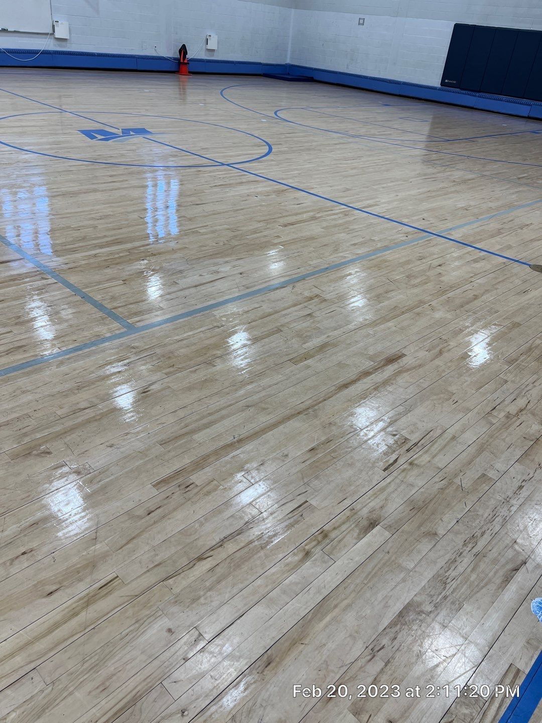 A basketball court with a wooden floor and blue lines.