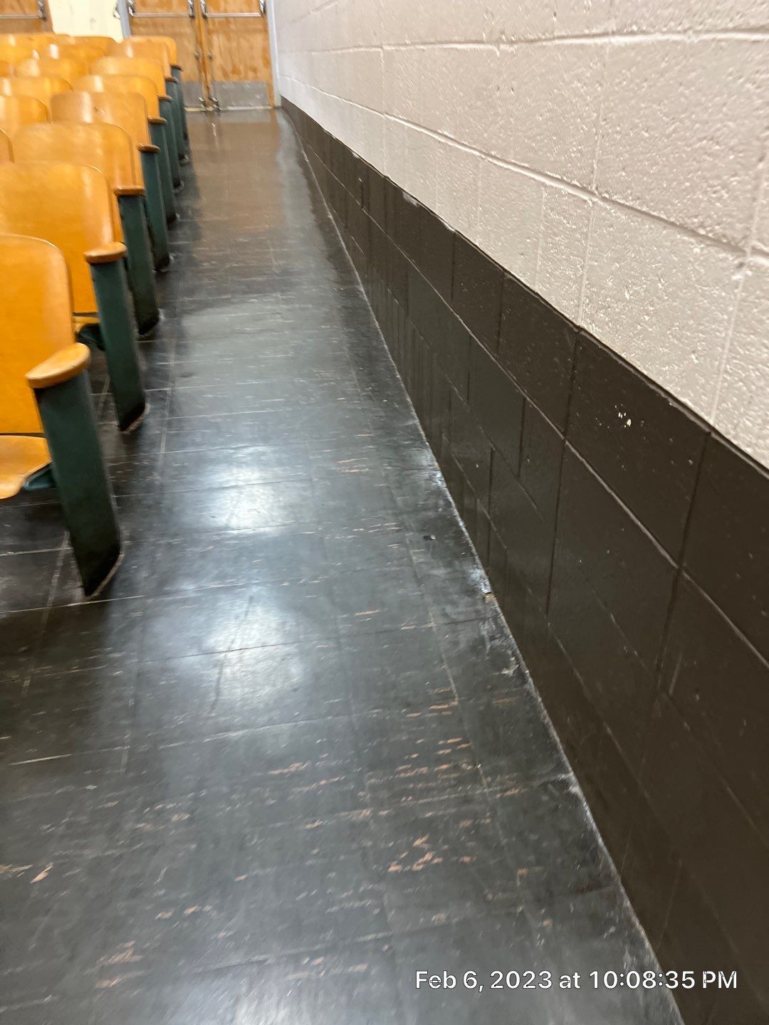 A row of chairs in an auditorium with a black floor.