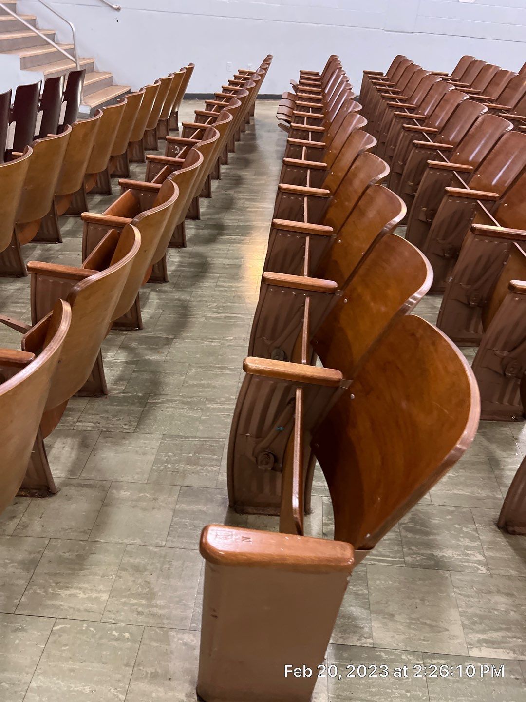 Rows of wooden chairs are lined up in an auditorium.