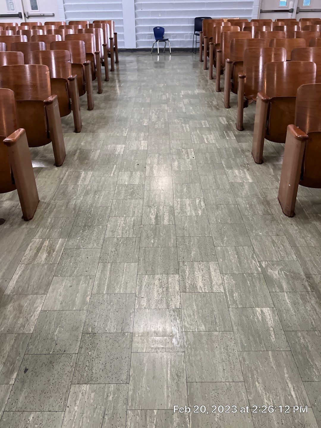 A row of wooden chairs are lined up in an auditorium.