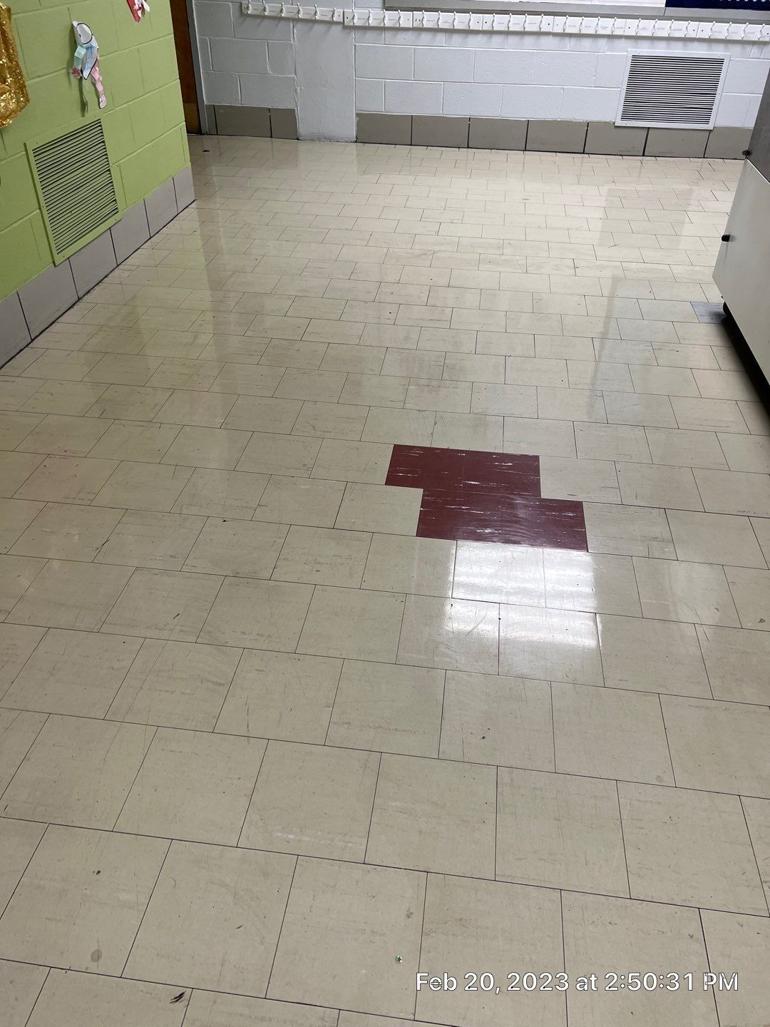 A room with a white tile floor and a red tile in the middle.