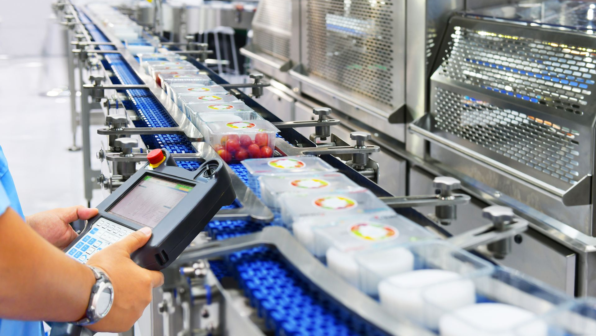Person operating control panel near a food packaging production line.