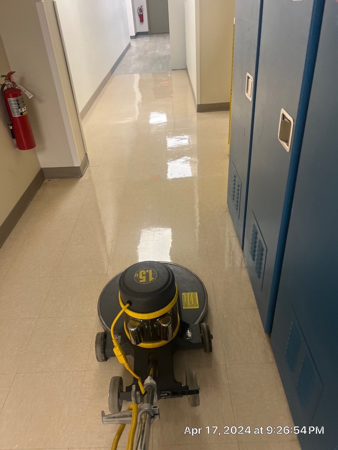 A machine is polishing a tile floor in a hallway.