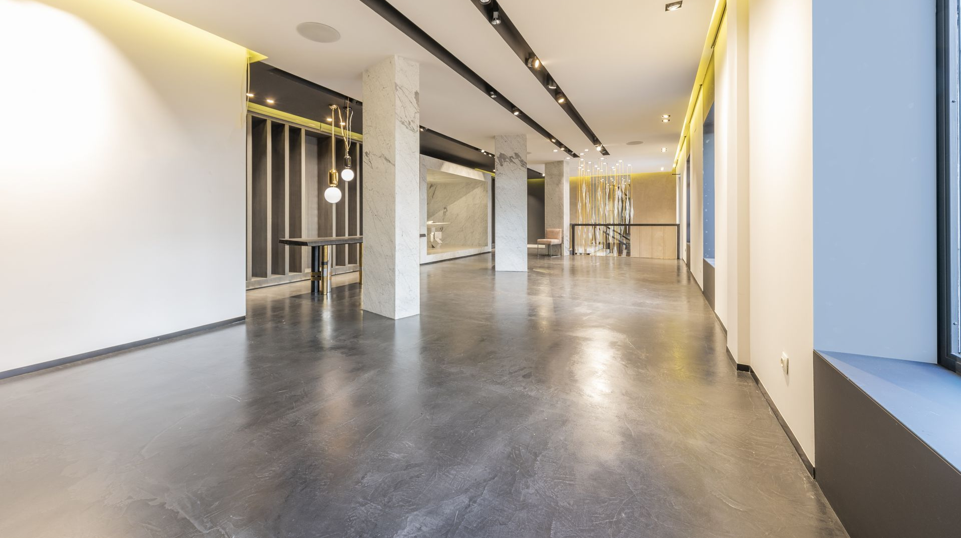 An empty, modern gallery space with polished concrete floors and white walls.