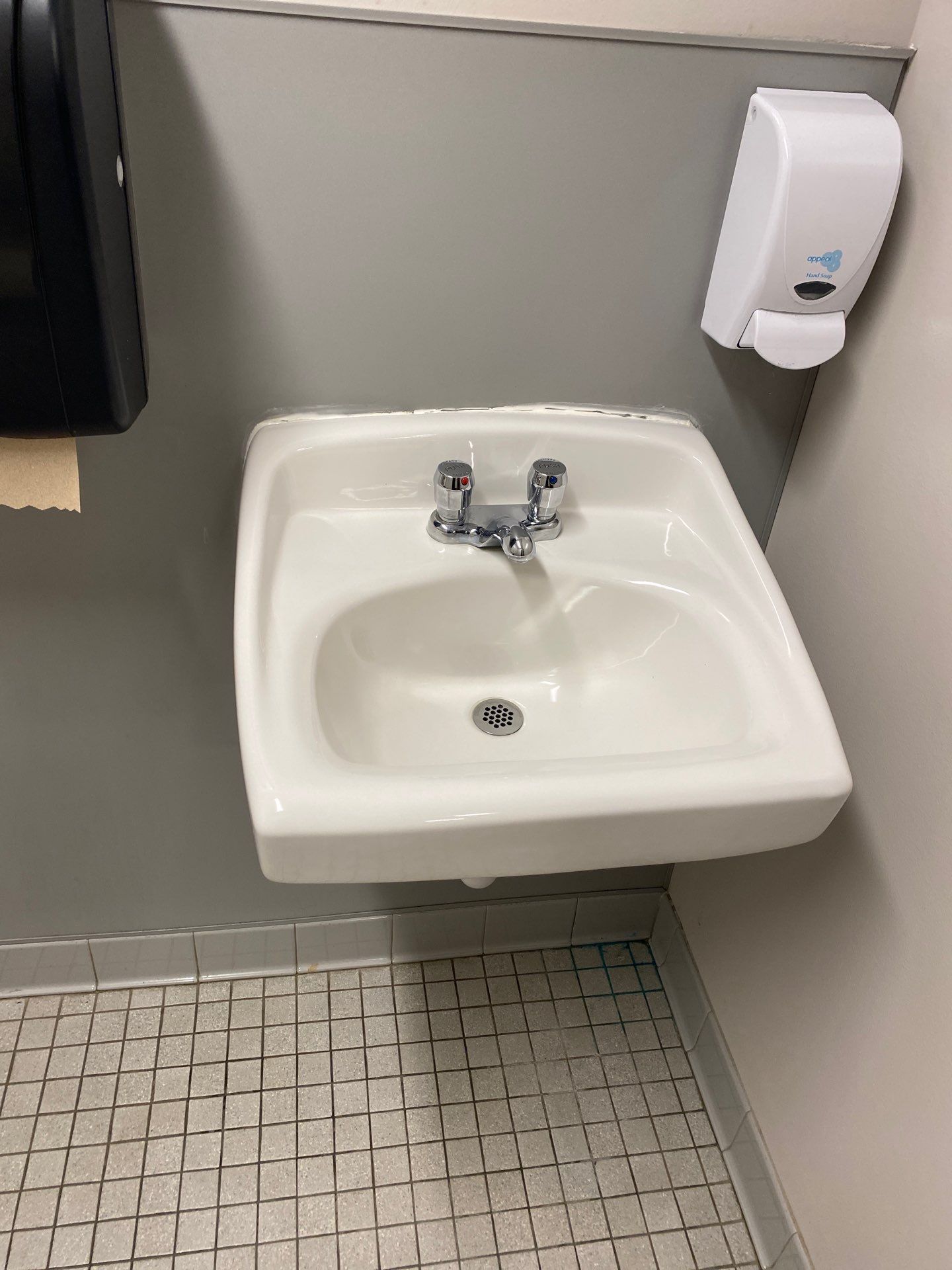 A bathroom sink with a soap dispenser next to it.