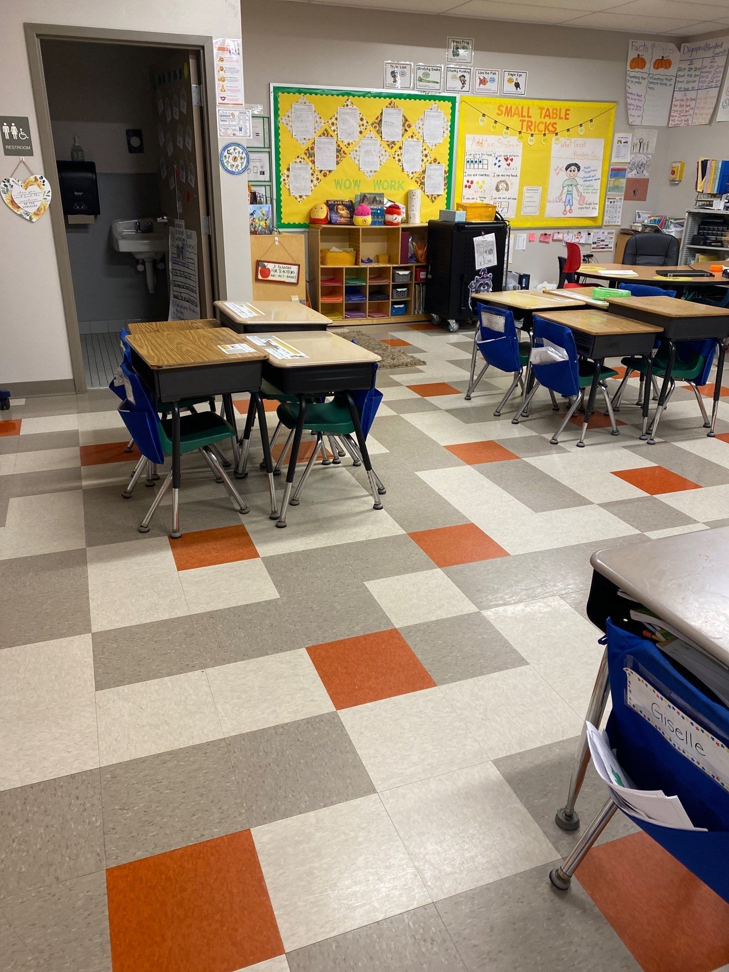 A classroom with tables and chairs and a checkered floor.