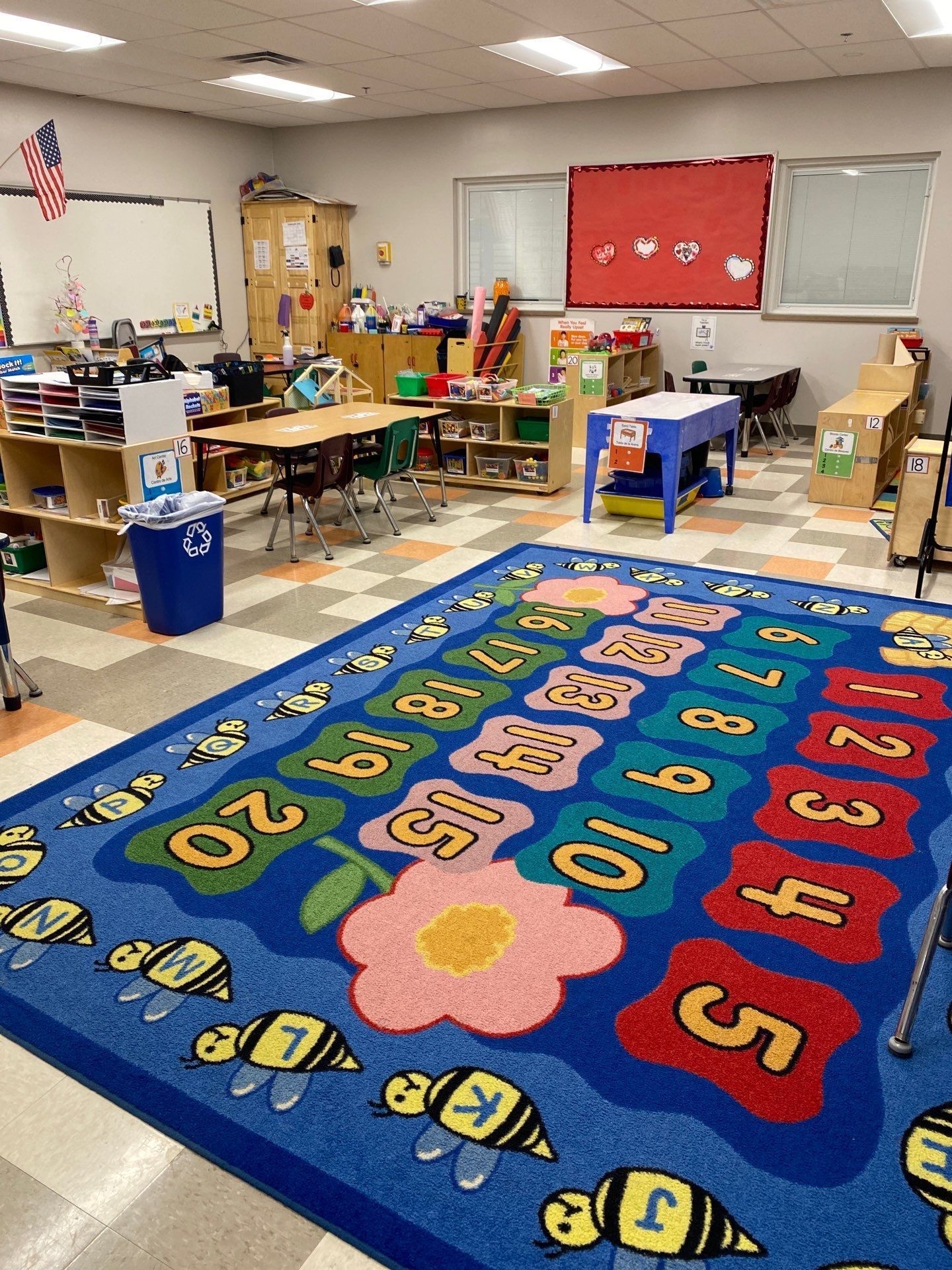 A classroom with a blue rug with numbers on it