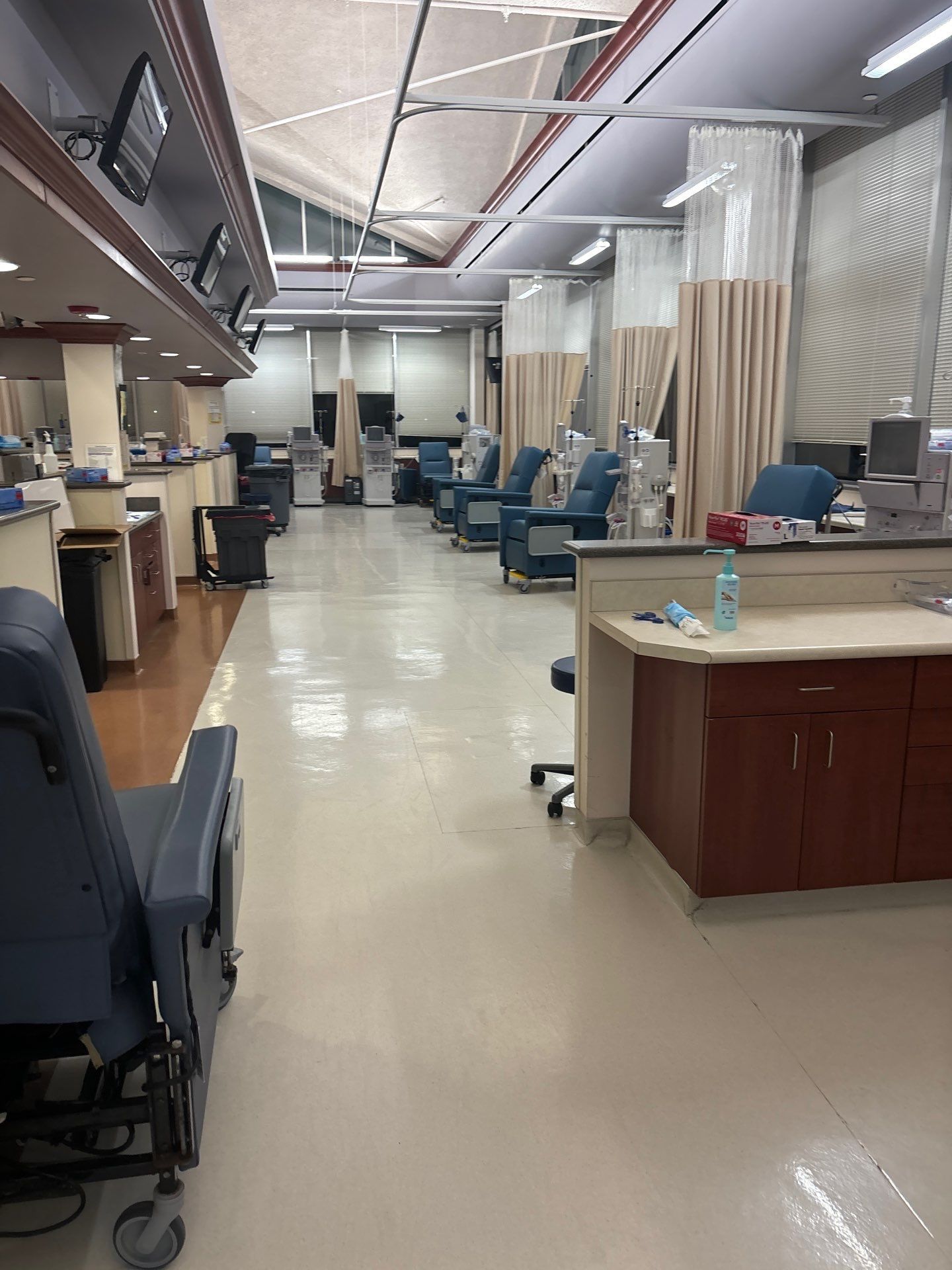 Dialysis treatment room with chairs, machines, and curtains.
