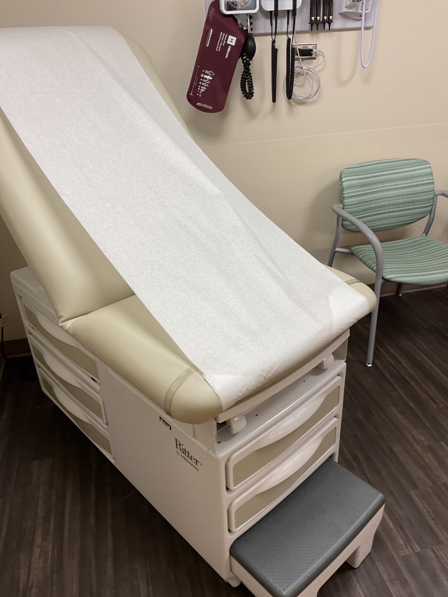 Medical exam room with an exam table, blood pressure monitor, and a chair.