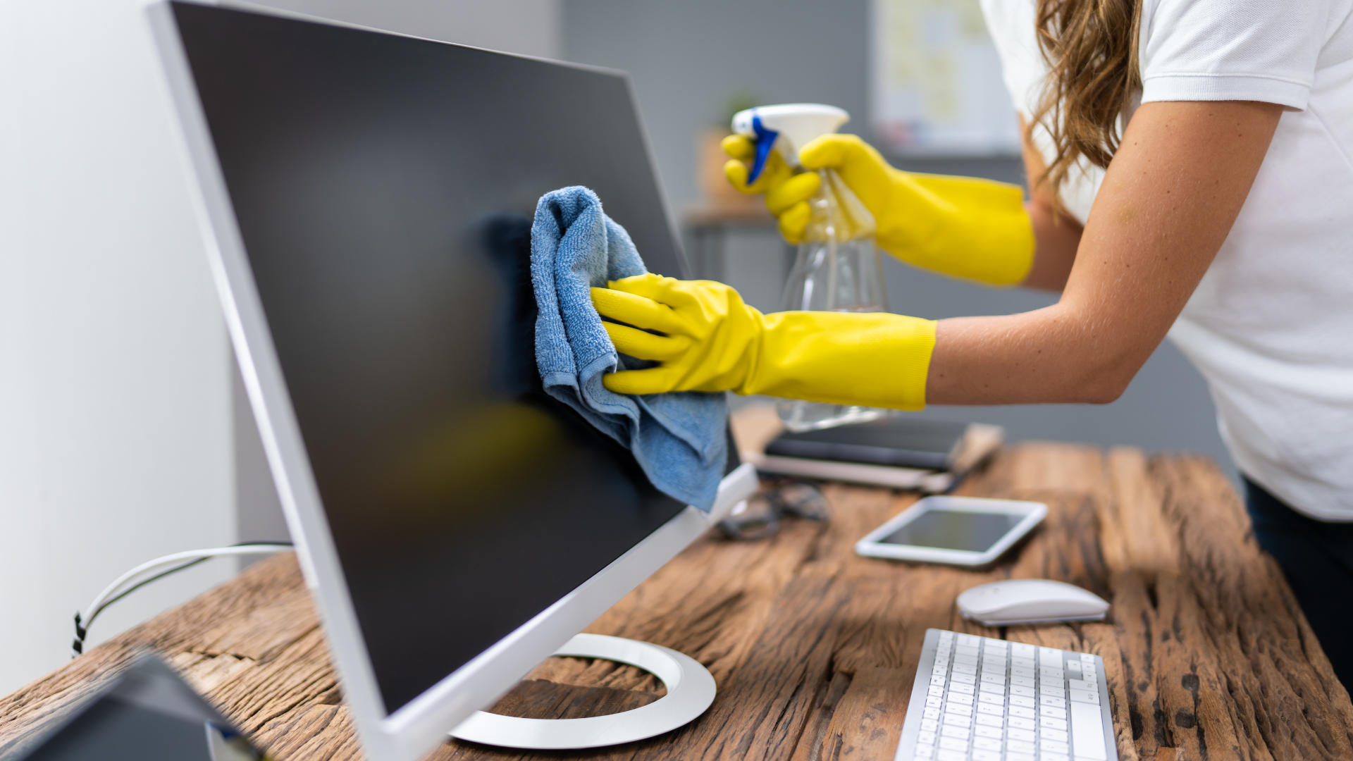 A person wearing yellow gloves is cleaning an office chair.