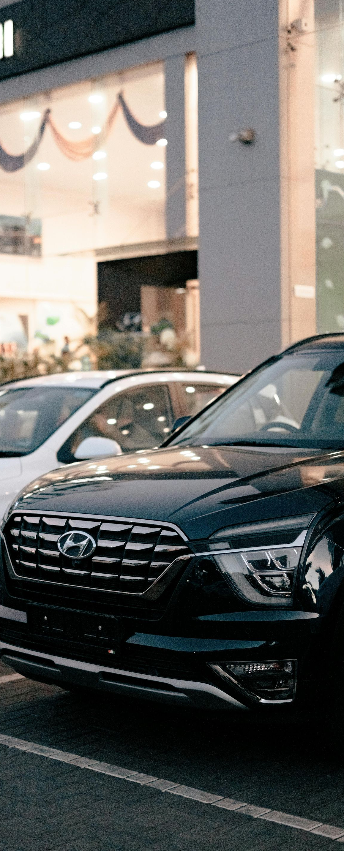 Hyundai cars parked outside a dealership, white and black cars in focus.
