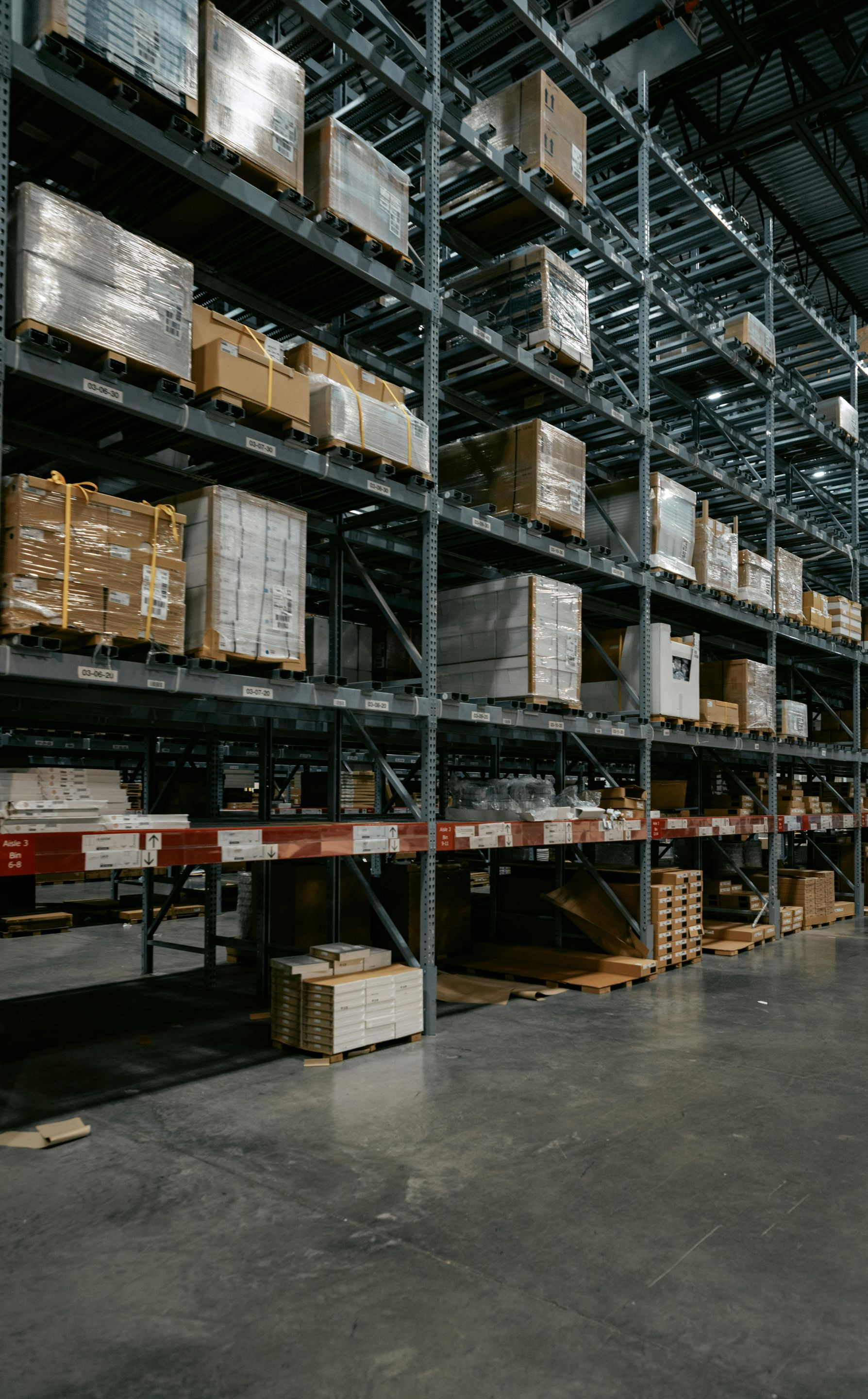 Warehouse interior with tall shelving packed with boxes and pallets.