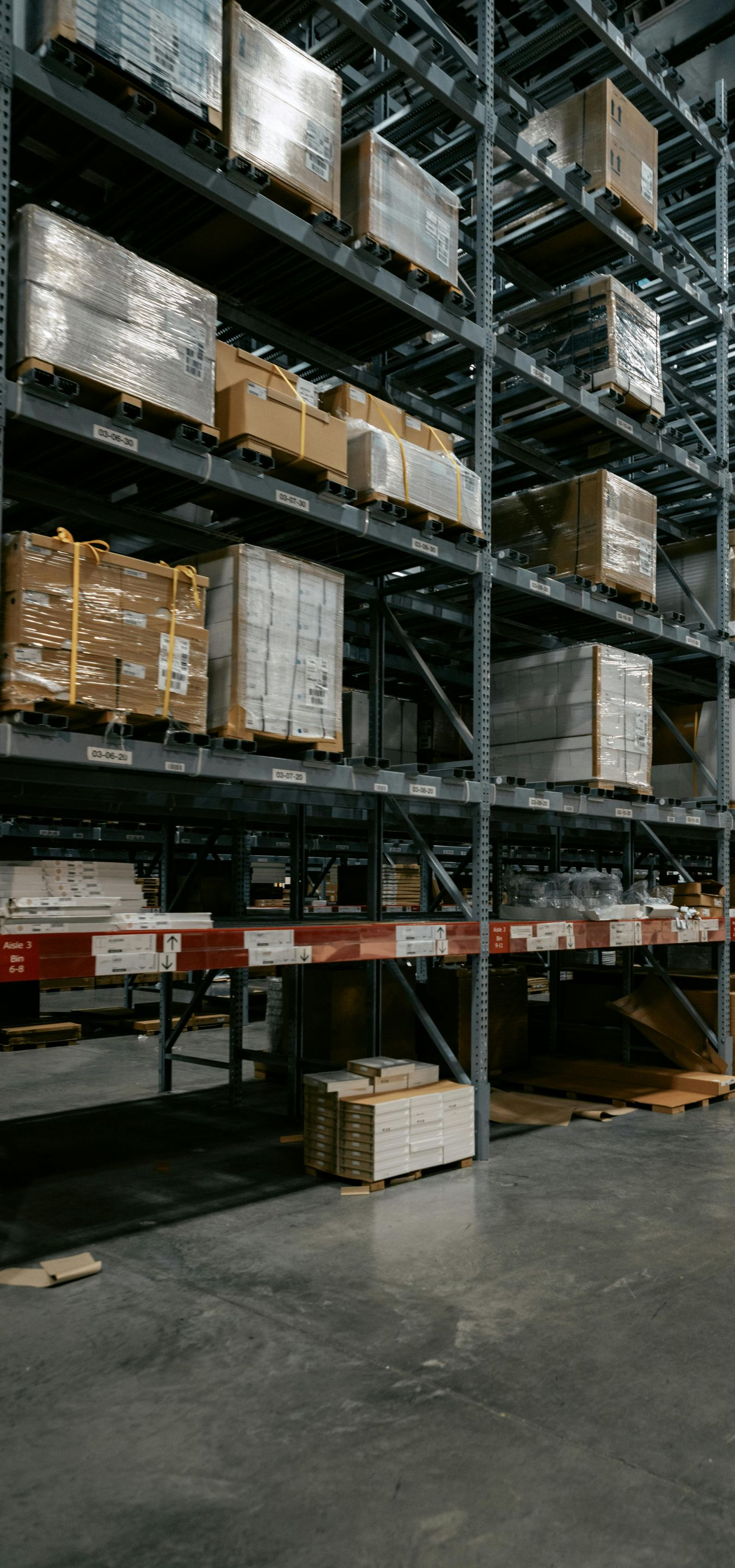 Warehouse shelves stacked with packaged goods. Metal framework against a concrete floor.