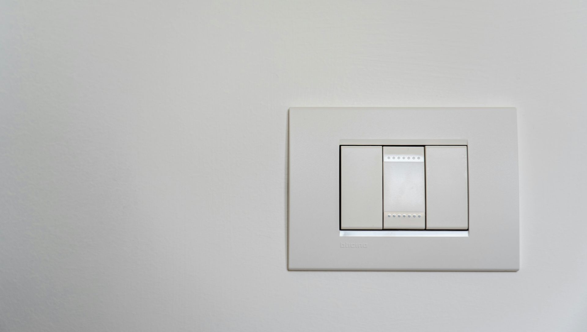 White light switch on a white wall, with three rectangular buttons.
