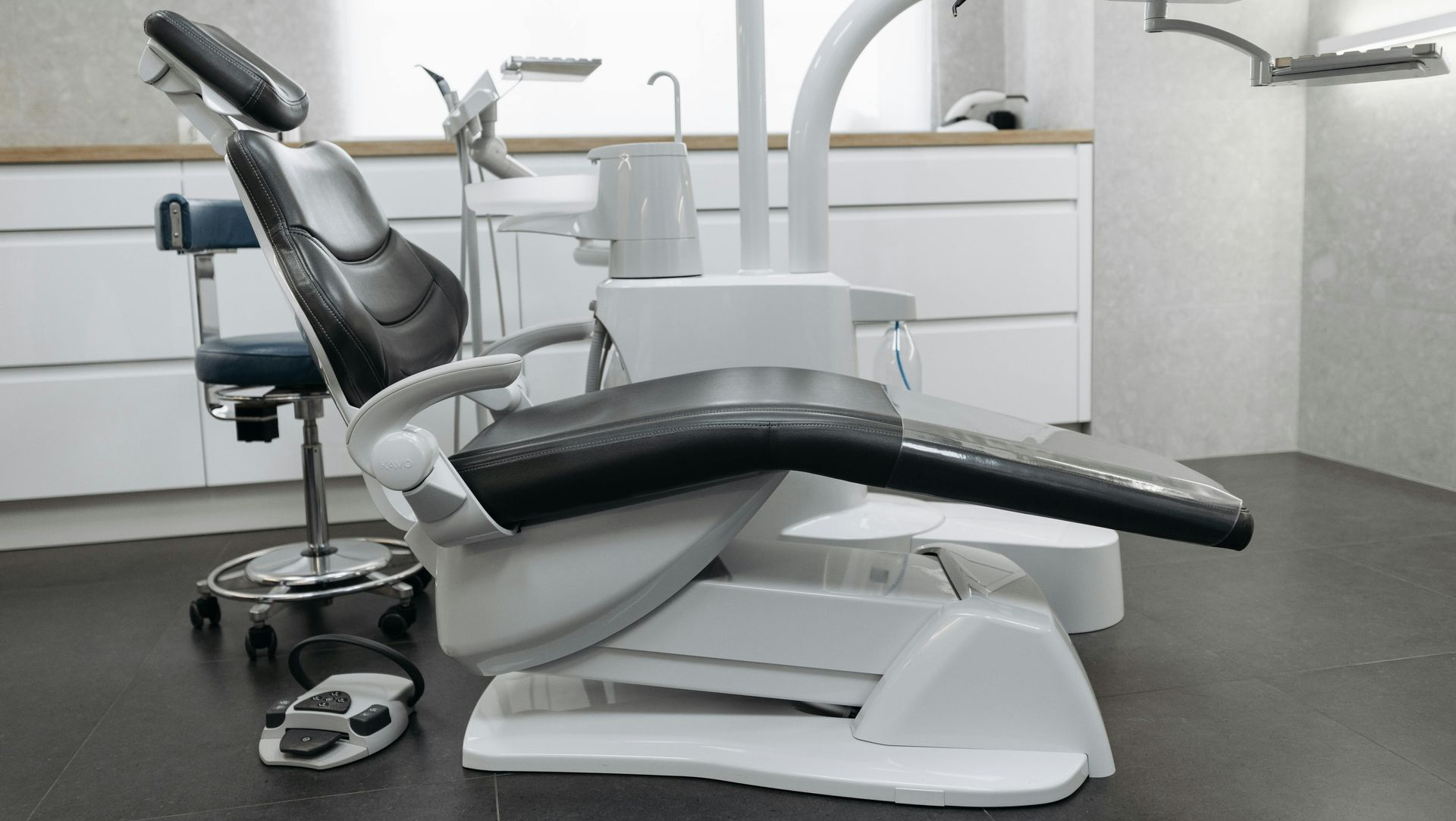 Dental chair in a bright, modern office setting. White and black chair with attached equipment.