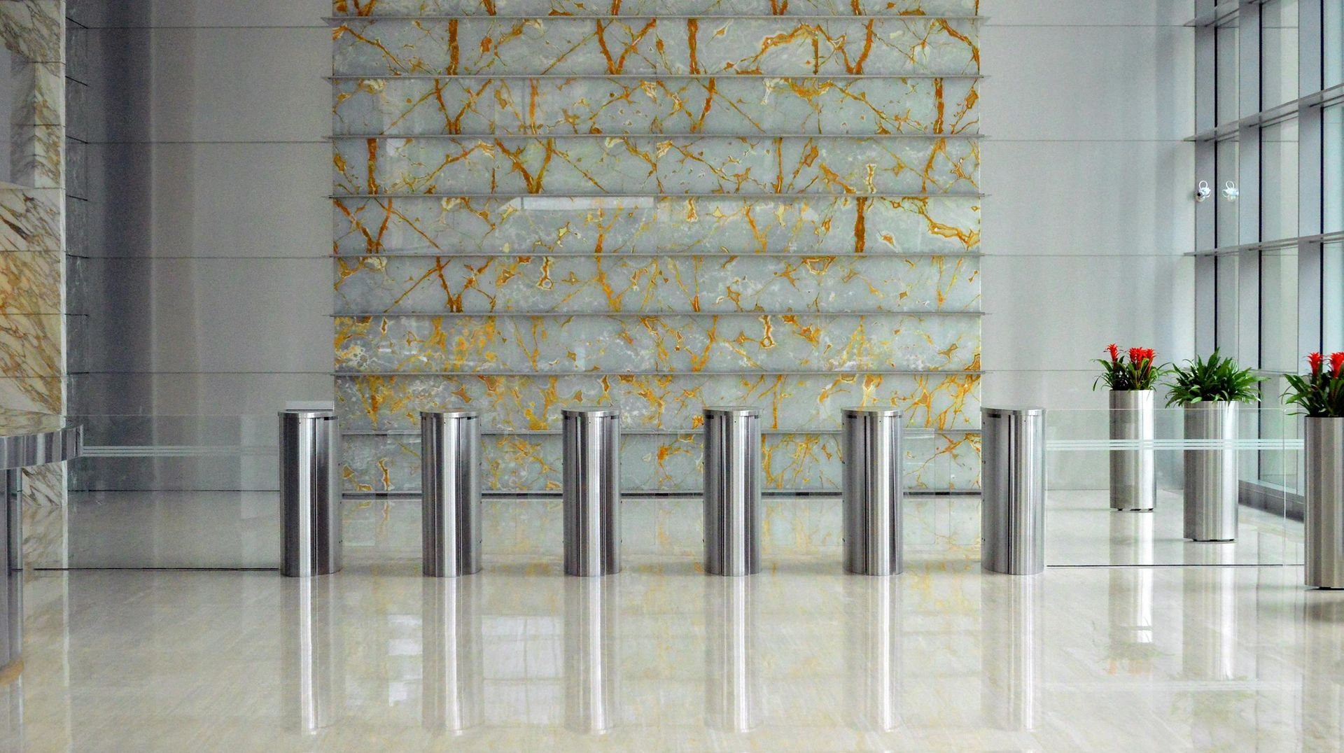 Polished lobby with security turnstiles, marble floor, and decorative stone wall.