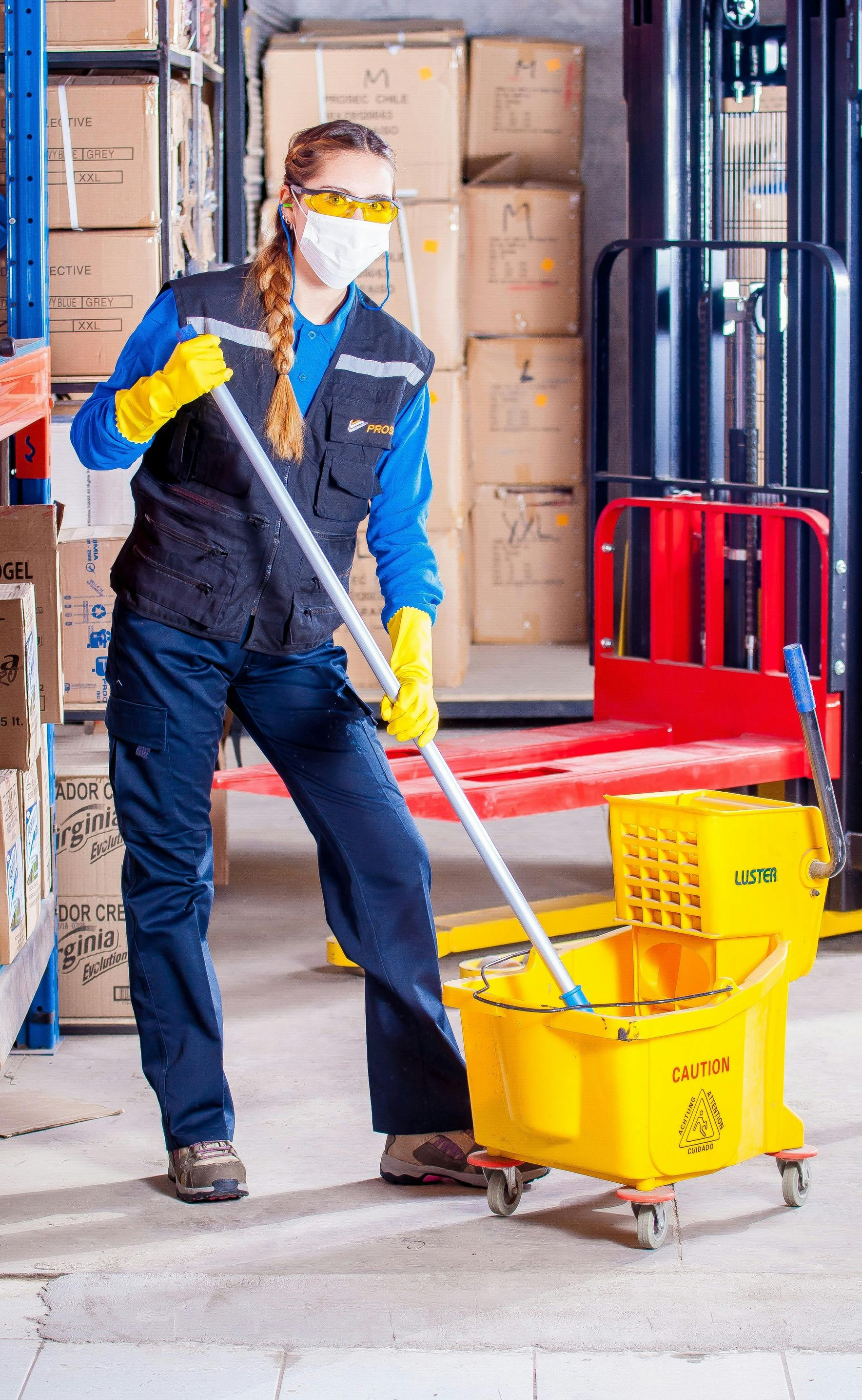 Person wearing safety gear mopping a warehouse floor.