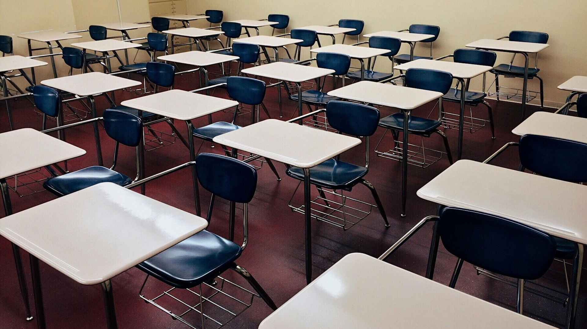 Empty classroom with rows of student desks and chairs.