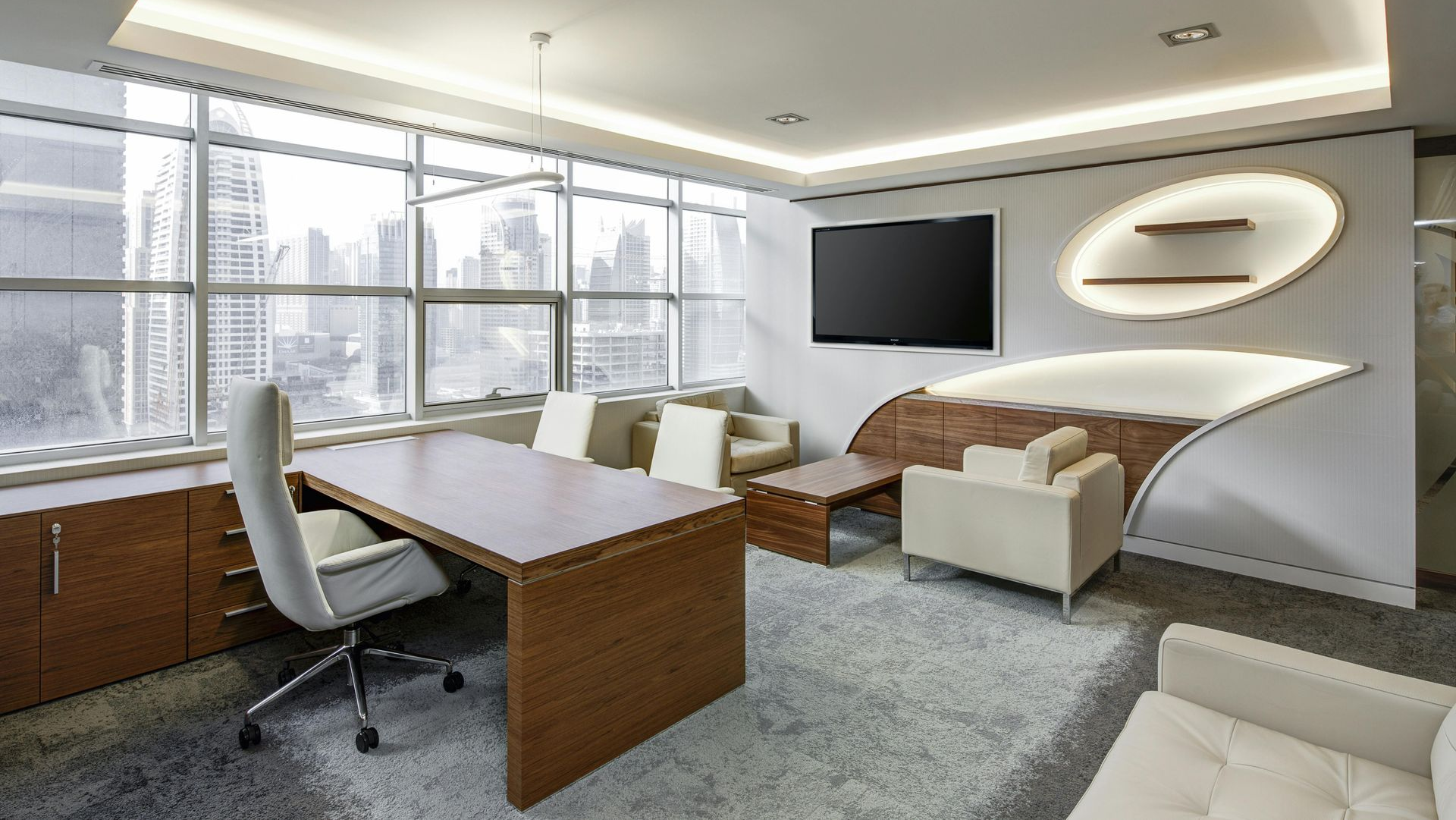 Modern office with desk, seating, large windows, and a cityscape view.