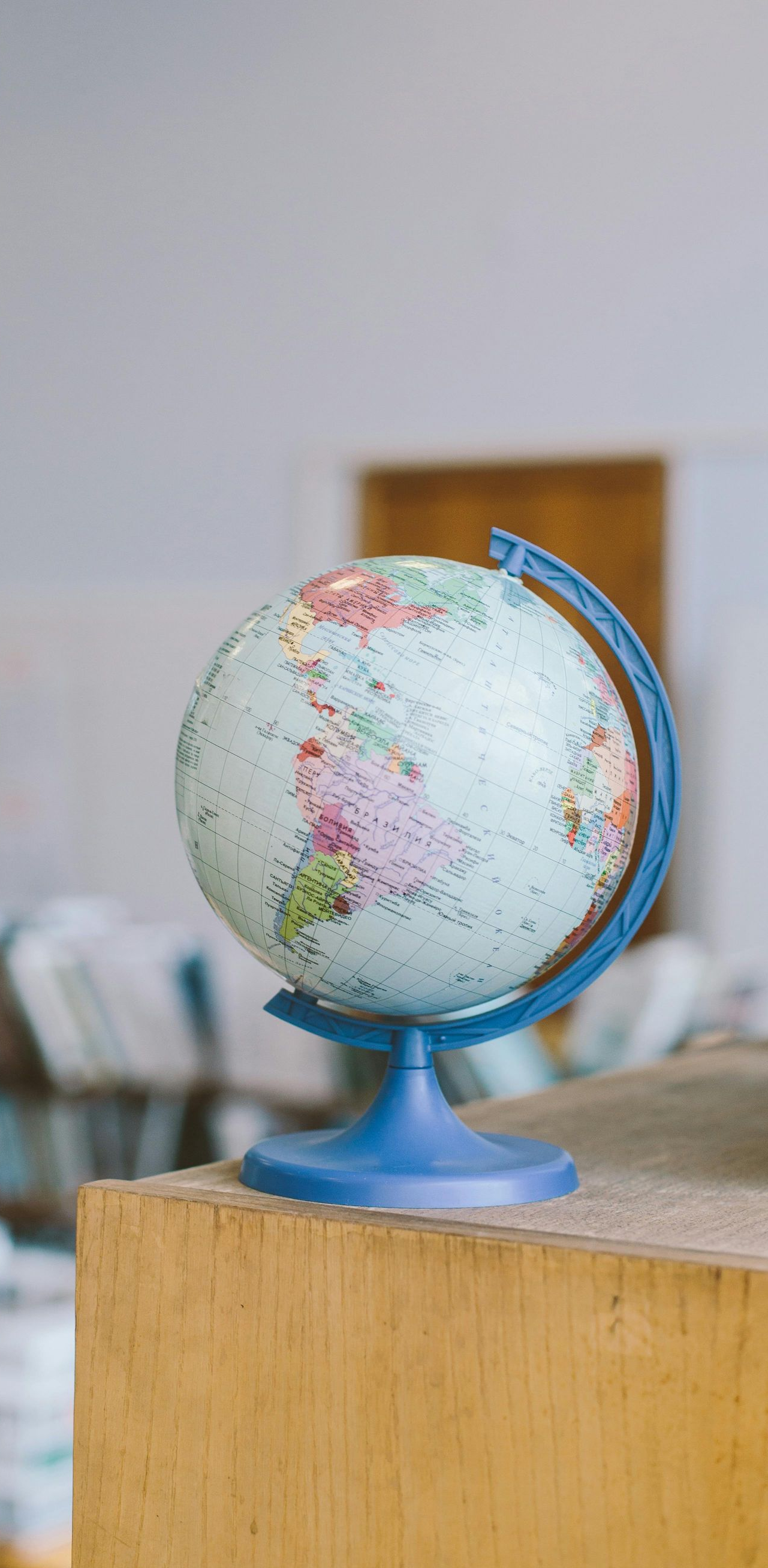 Blue and white globe on a wooden surface, set in a room with a blurred background.