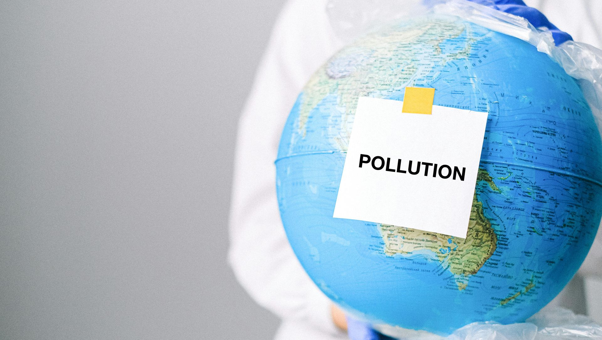 Person holding a globe wrapped in plastic, with a note reading