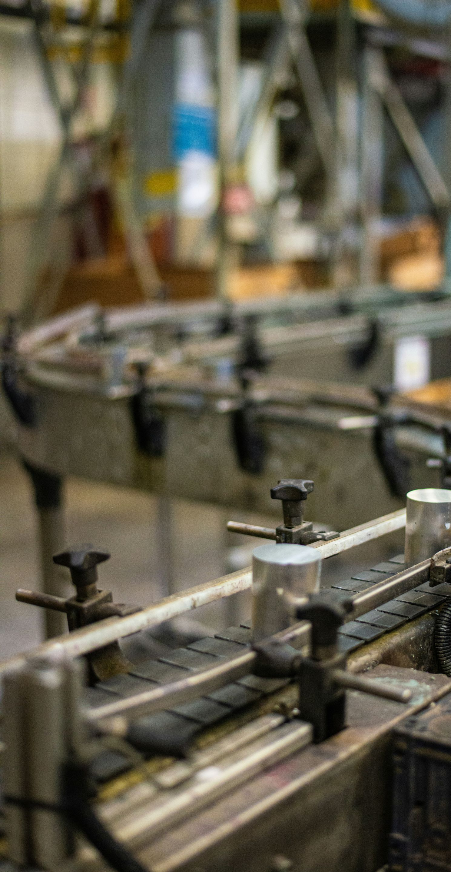 Conveyor belt in a factory, carrying cylindrical metal cans along a curved path.