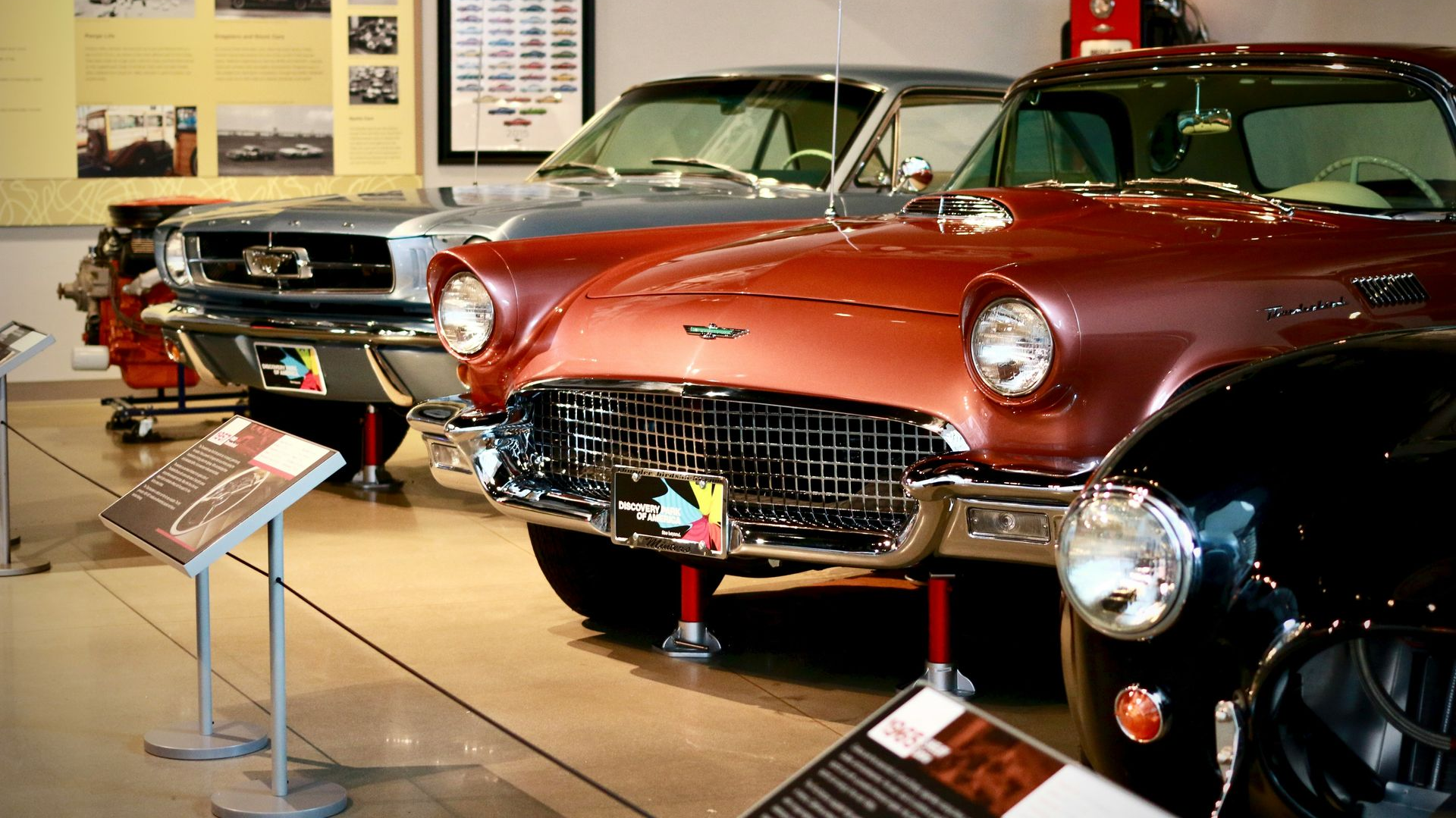 Classic cars on display in a museum with informational signs.