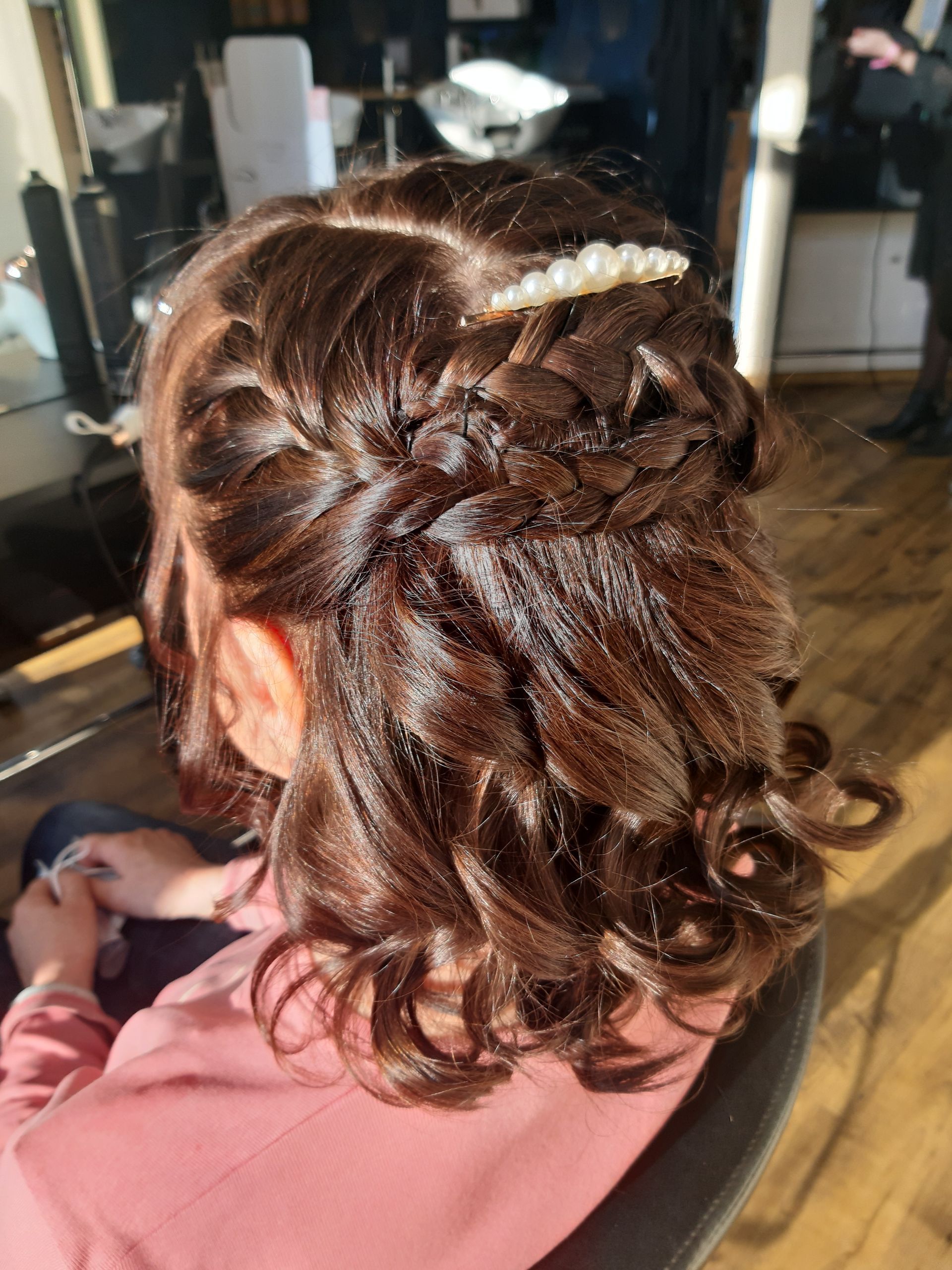 Une femme est assise sur une chaise avec ses cheveux mi-hauts mi-bas.