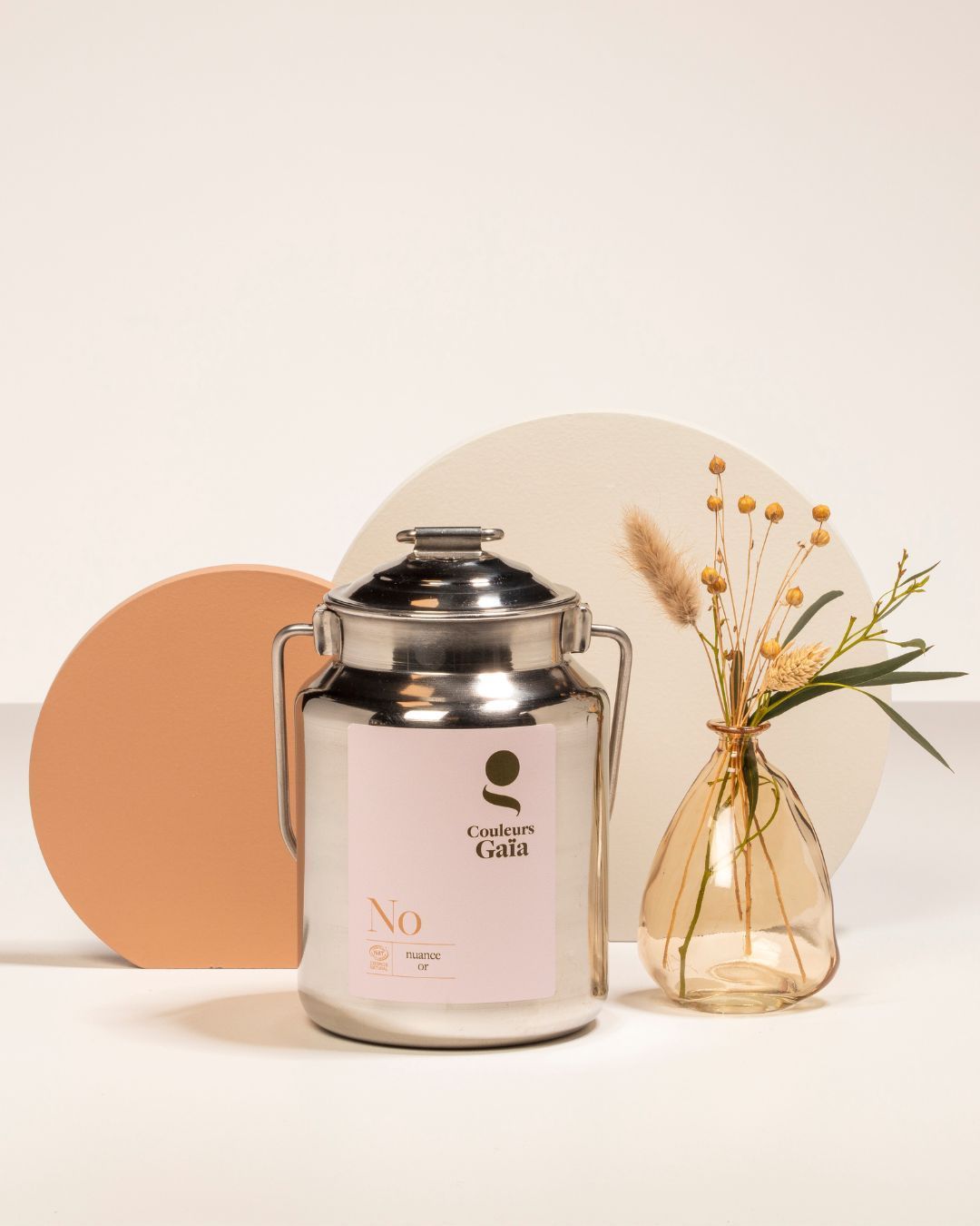 Un bidon de lait en acier inoxydable est posé sur une table à côté d'un vase de fleurs.