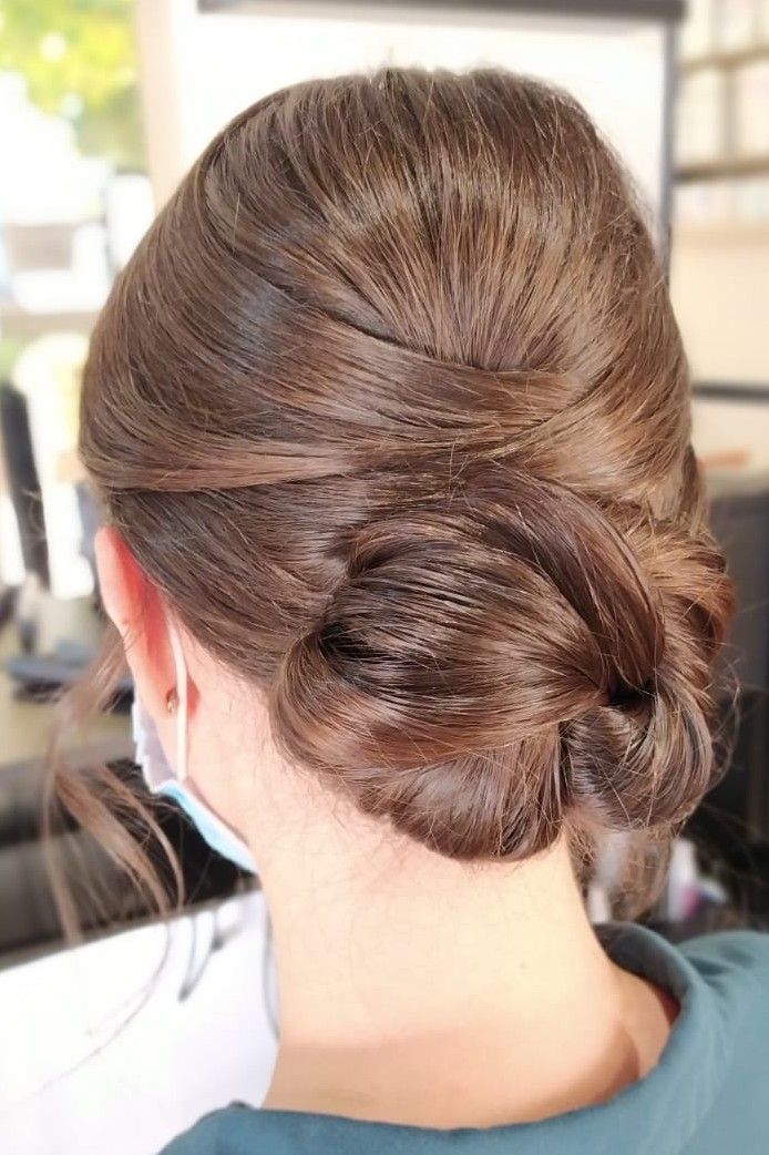 Une femme porte un masque et a les cheveux en chignon.
