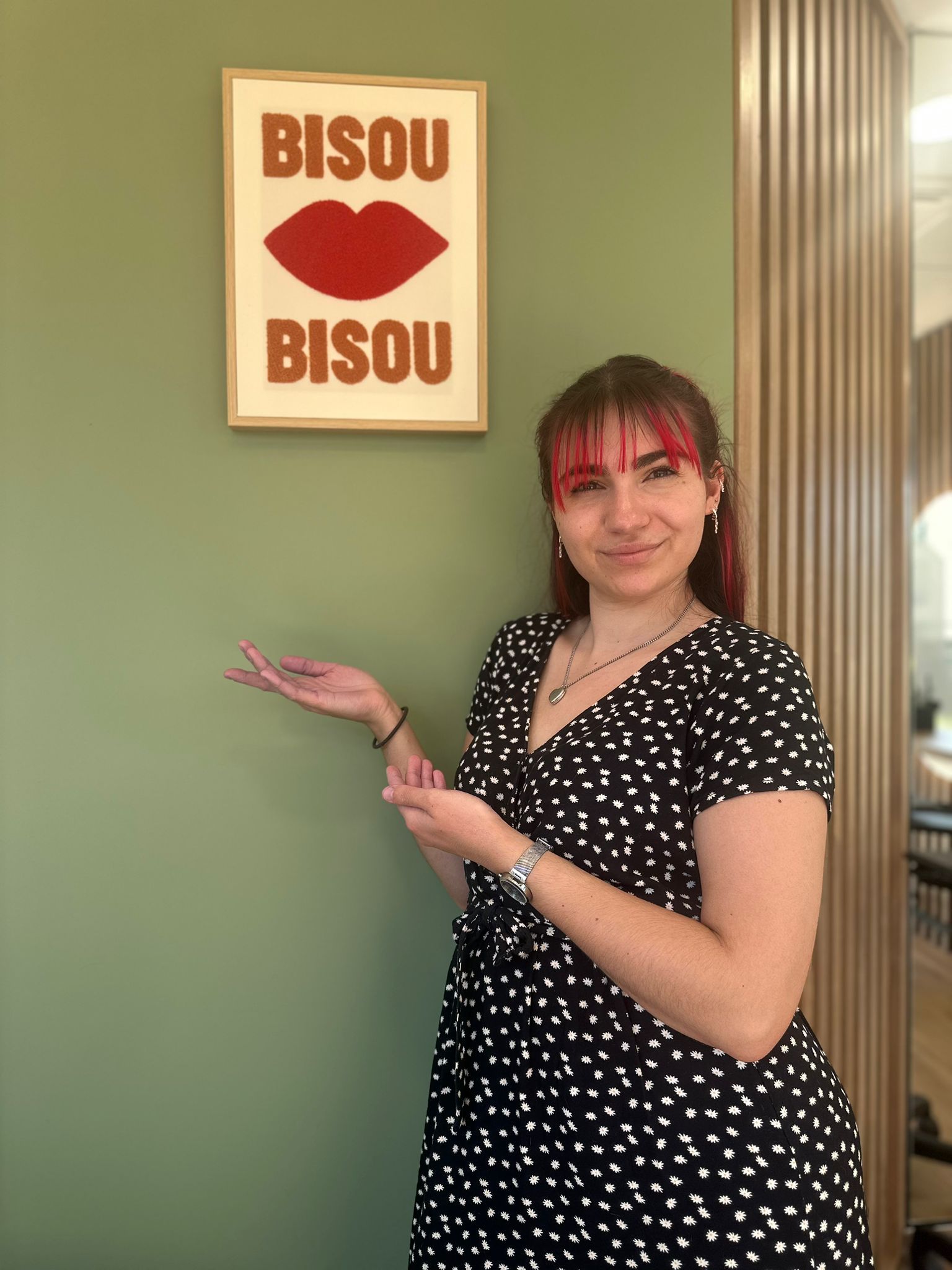 Une femme portant une chemise noire et un collier sourit à la caméra.