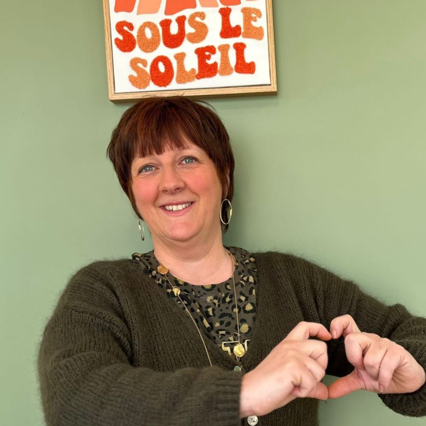 Une femme portant des lunettes et une chemise noire sourit à la caméra.