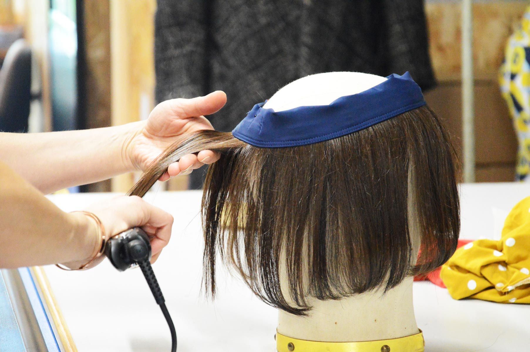 Une personne tient une perruque sur une tête de mannequin.