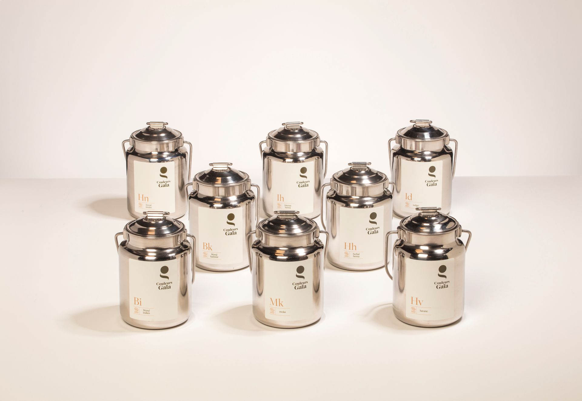 Un groupe de récipients en acier inoxydable avec couvercles sont alignés sur une table.