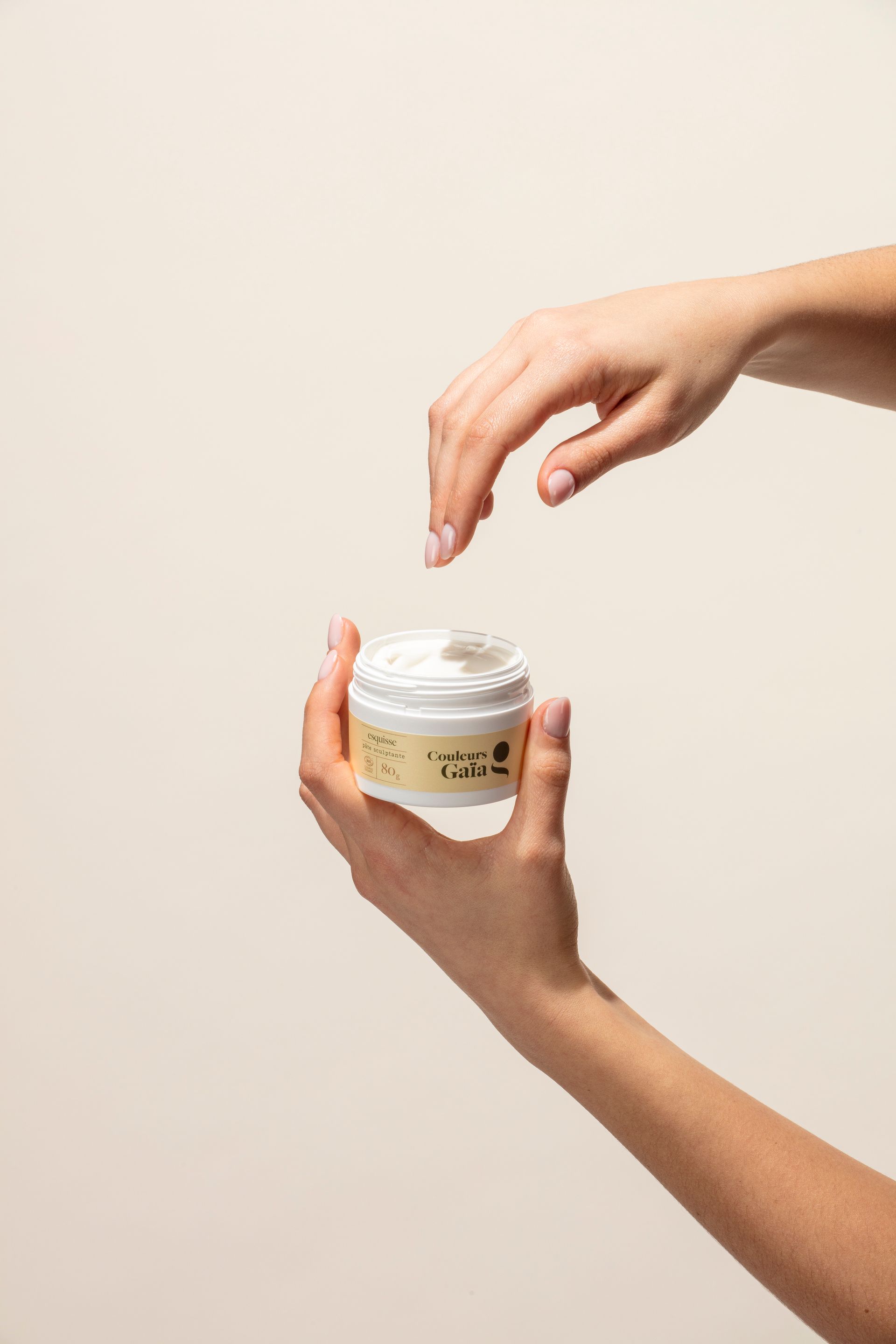 Une femme tient un pot de crème dans ses mains.