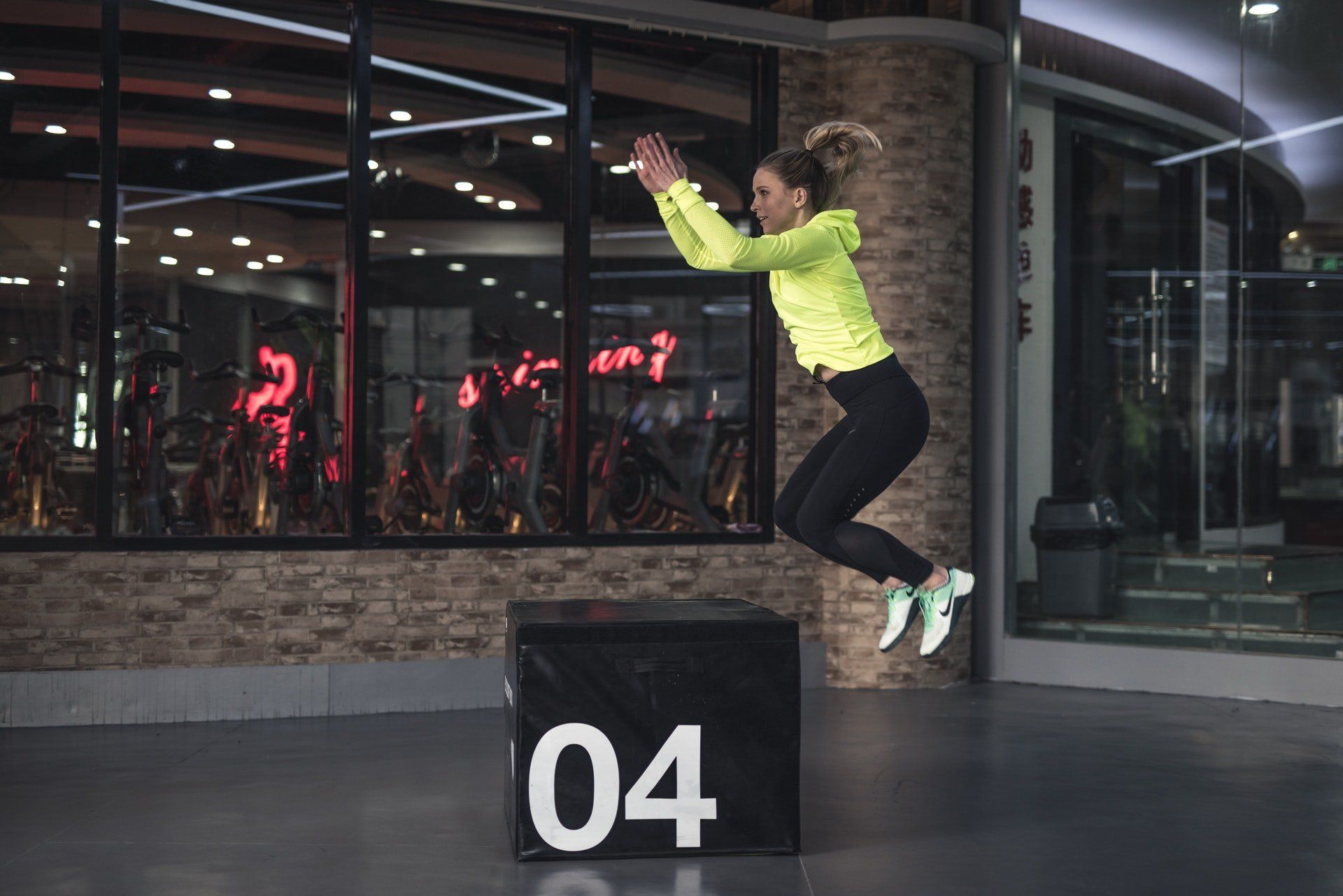 A woman is jumping over a box in a gym.