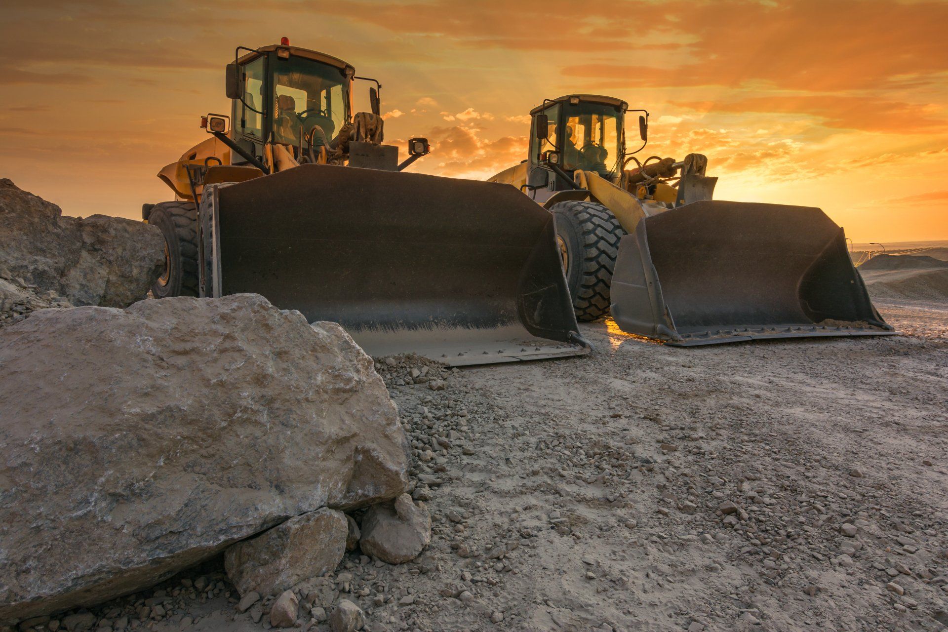 Deux bulldozers travaillent sur un chantier de construction au coucher du soleil.