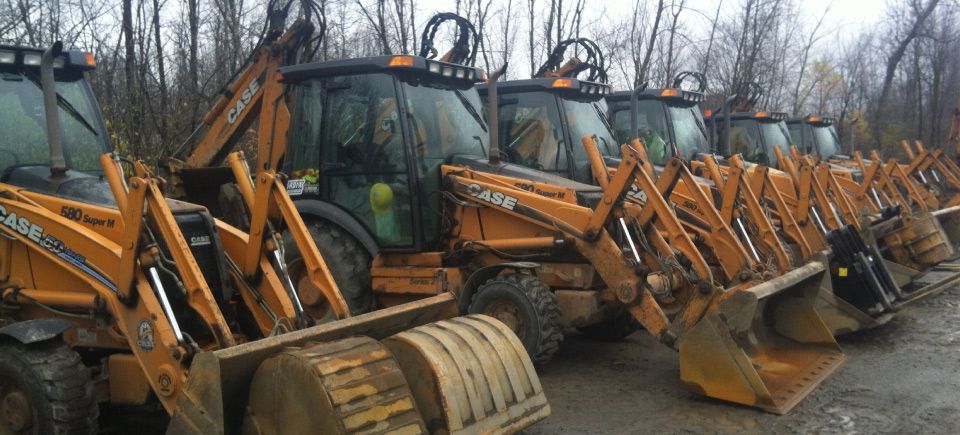 Une rangée de tracteurs garés les uns à côté des autres sur un chemin de terre.