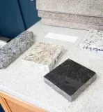Countertop with granite and carpet samples; neutral colors, lit interior.