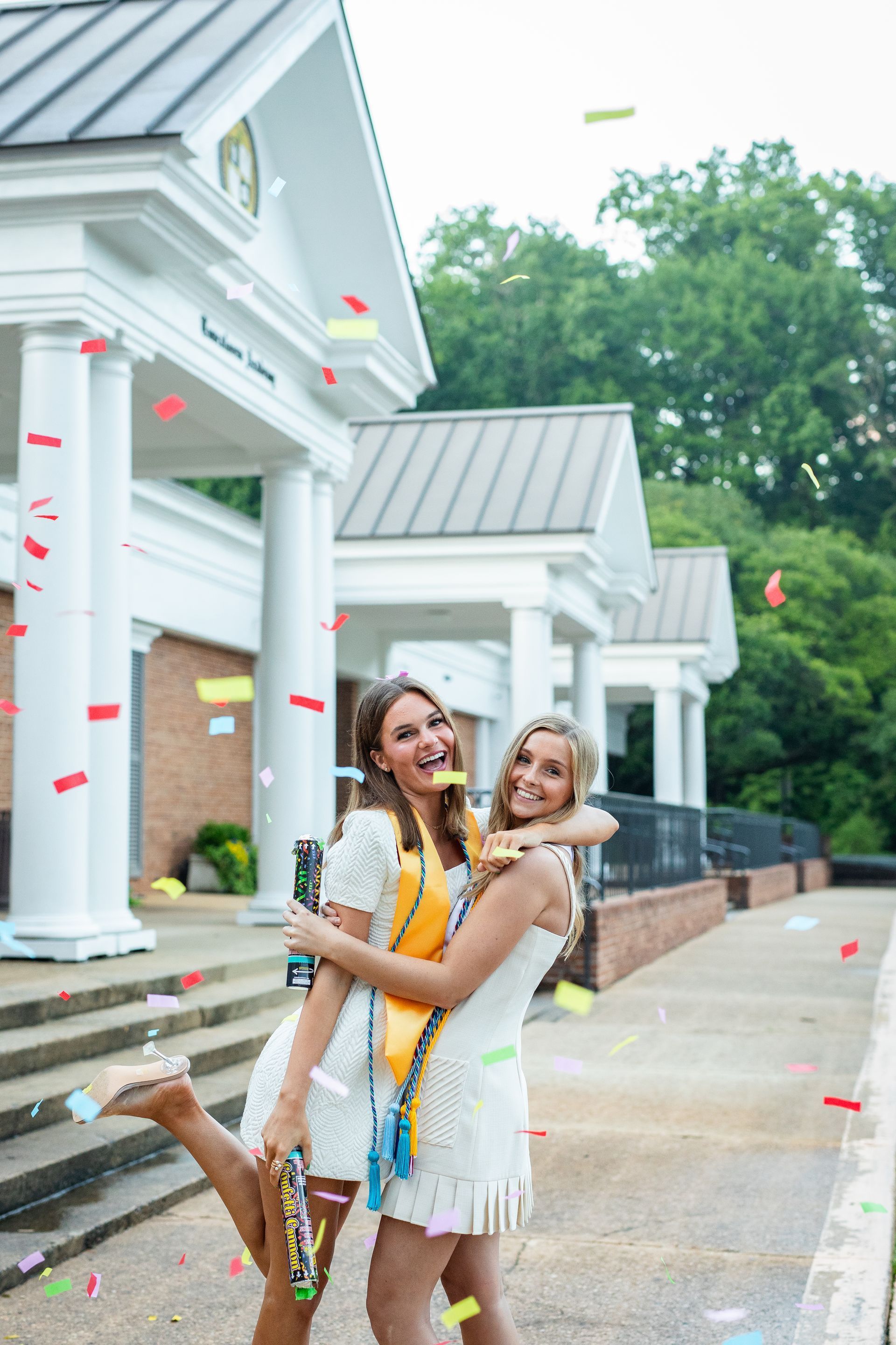 Two women are posing for a picture in front of a building.