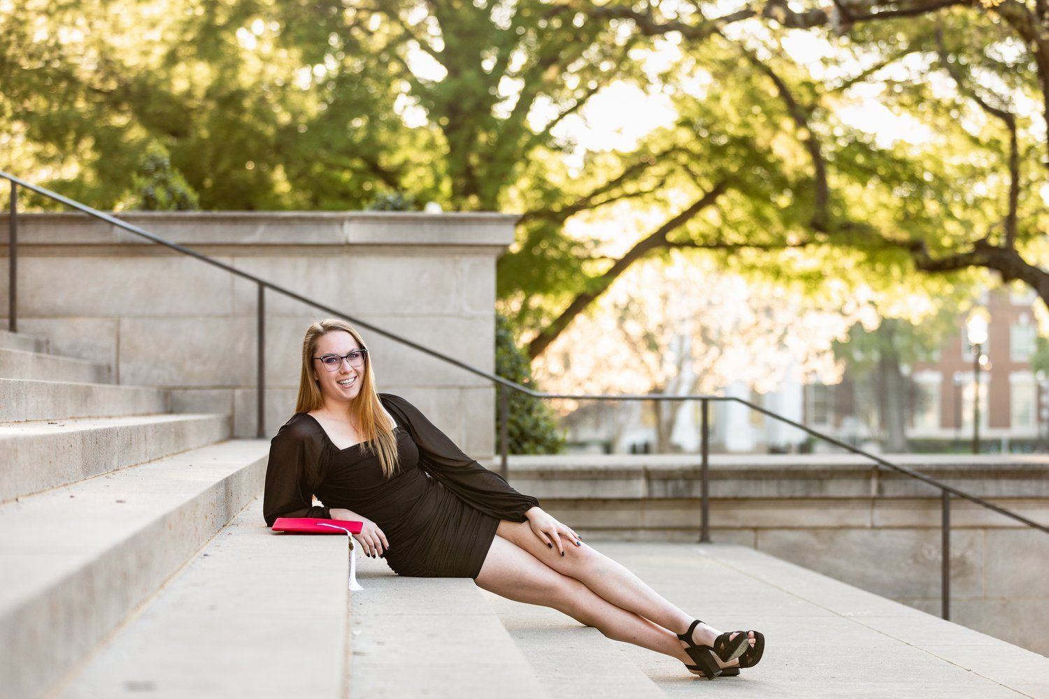 A woman in a black dress is laying on a set of stairs.