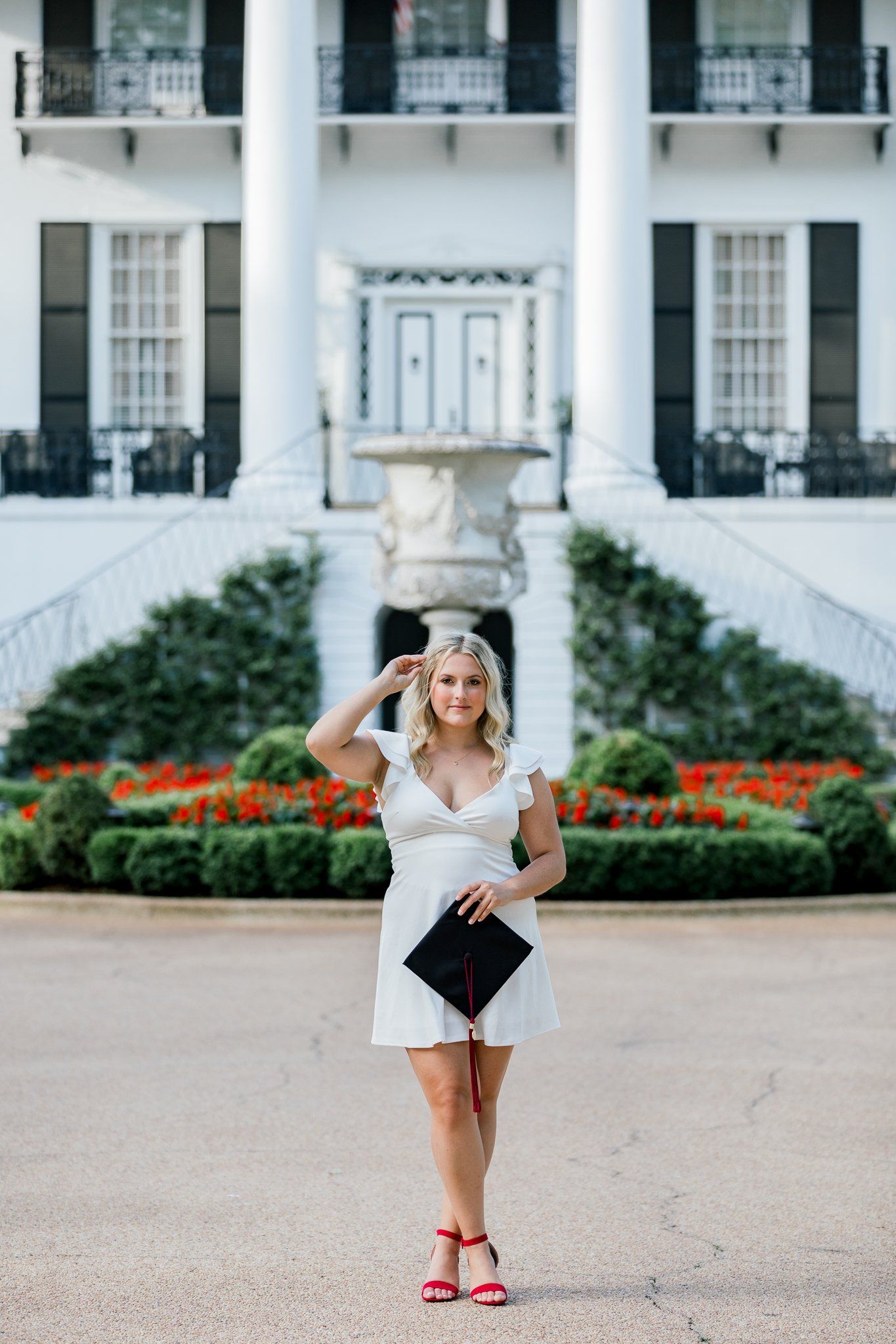 A woman in a white dress is standing in front of a large white building.