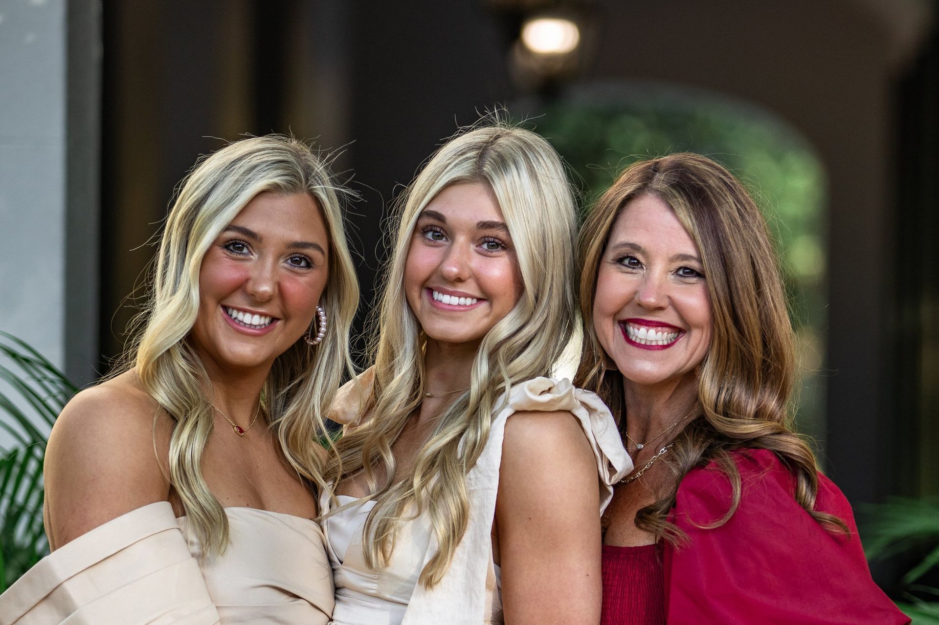 Three women are posing for a picture together and smiling for the camera.