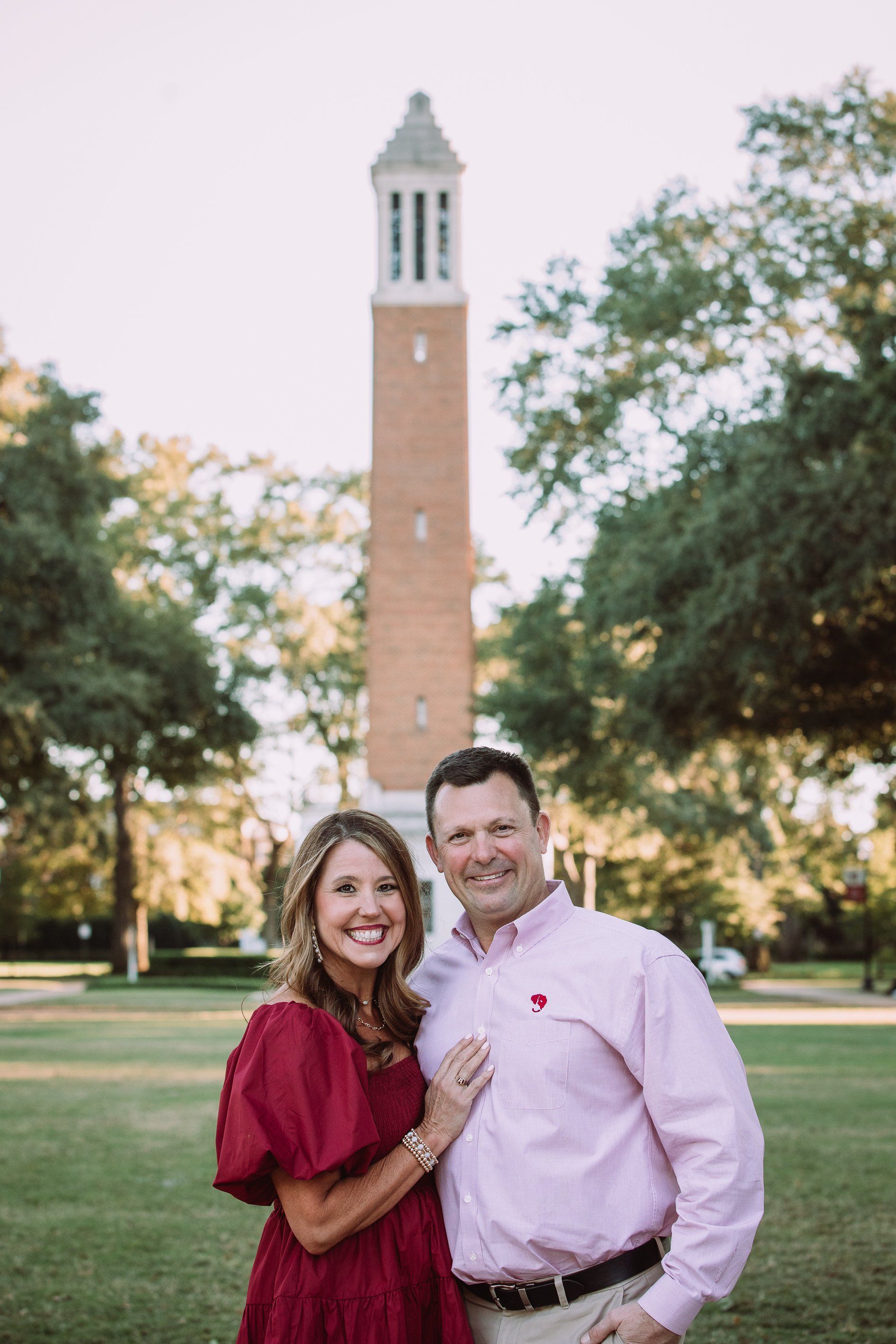 A man and a woman are posing for a picture in front of a clock tower.