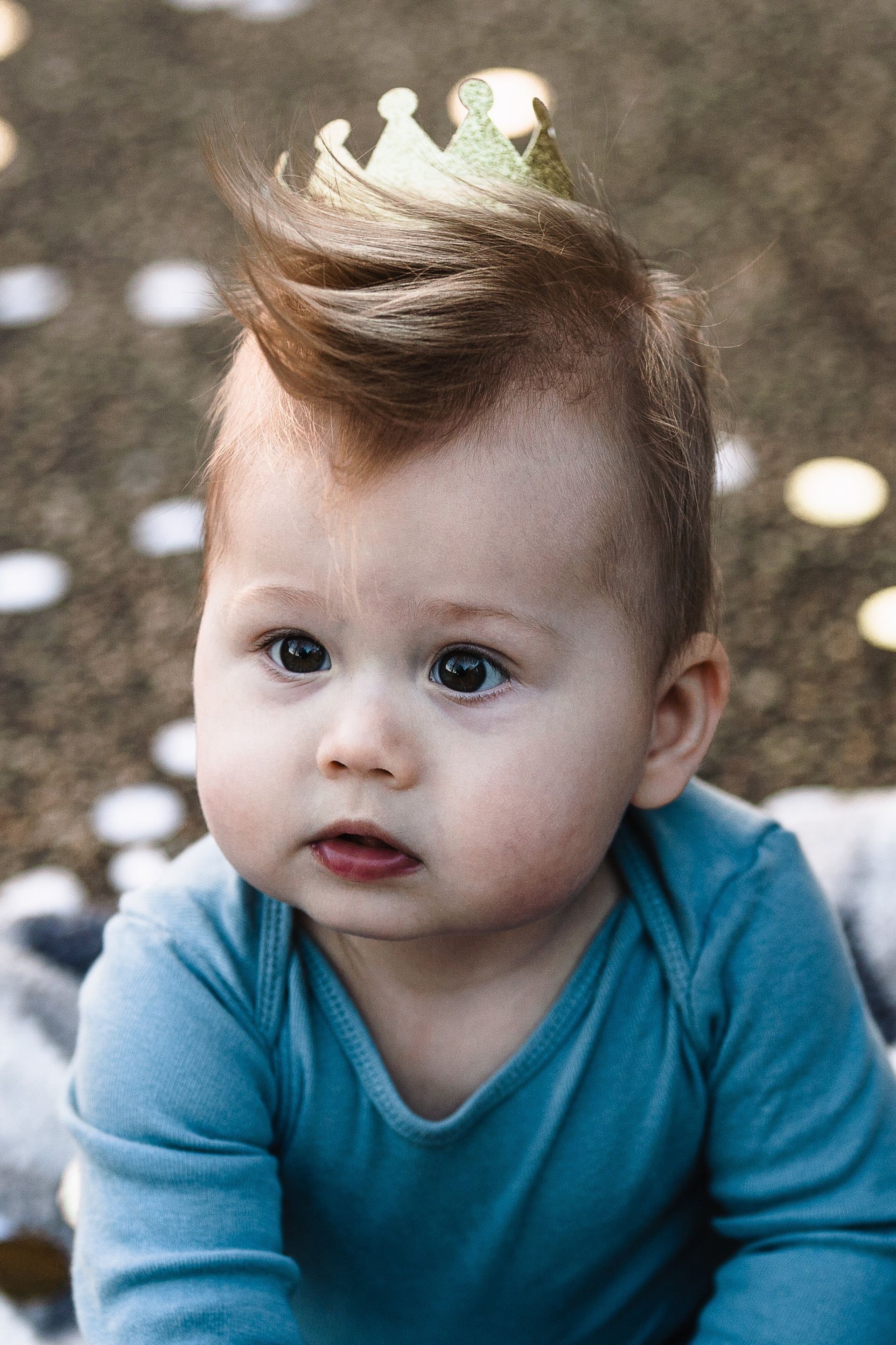 A baby with a mohawk and a crown on his head.